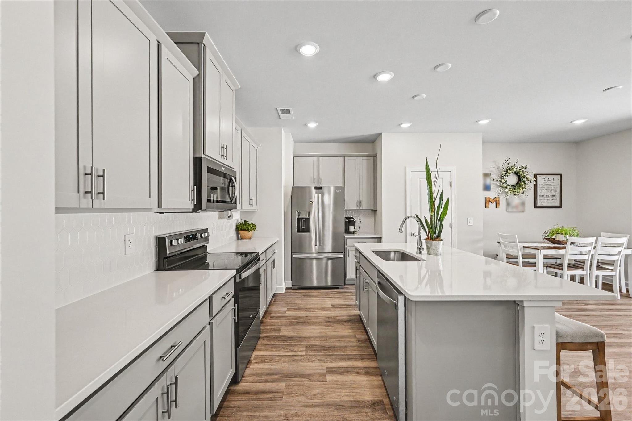The kitchen is crisp and clean, featuring stainless appliances, abundant cabinet + counter space, and an island with breakfast bar. - 408 Luna Lane, Shelby