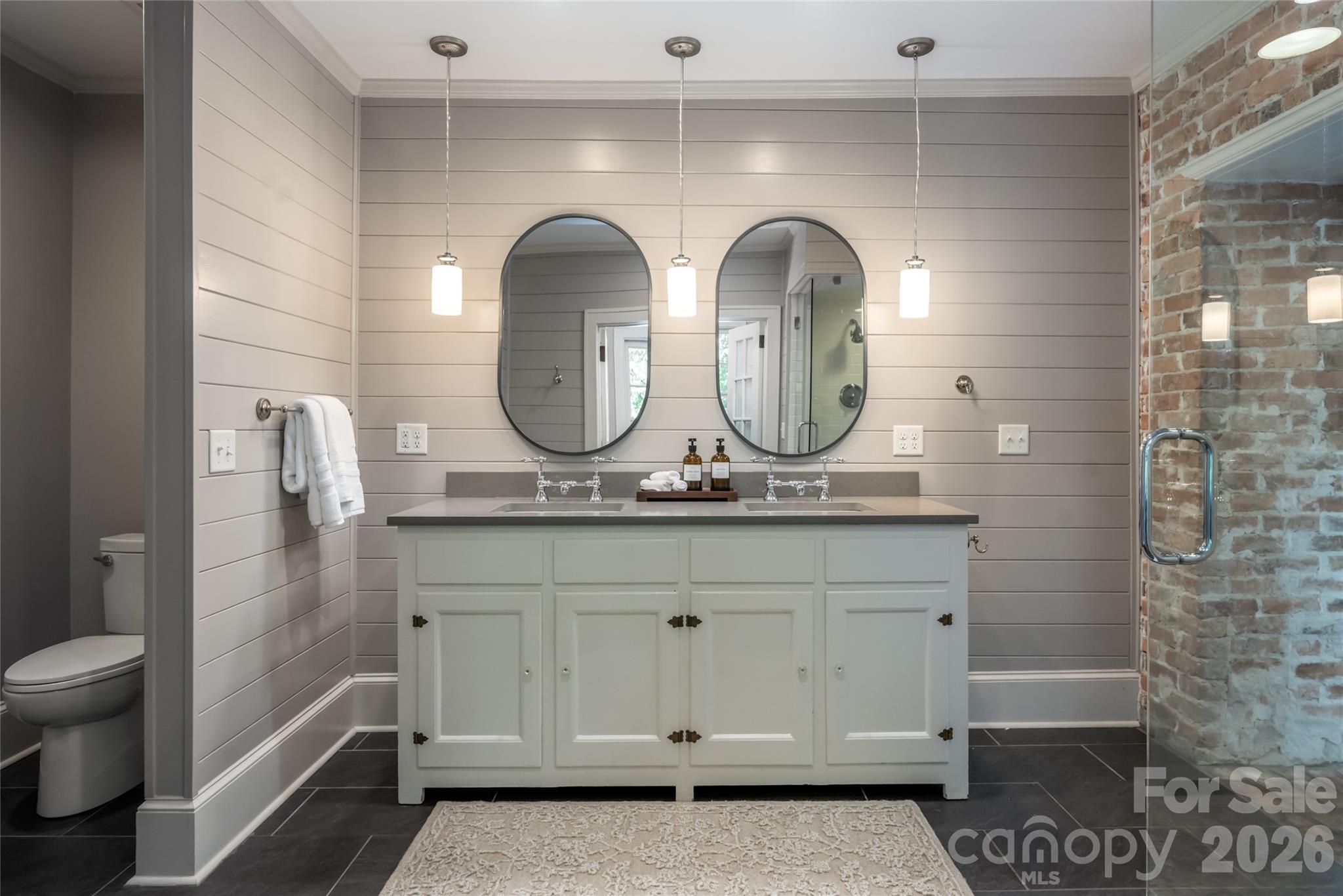 The primary bathroom features exposed brick that adds to the character of the home. - 35 Elias Place, Asheville