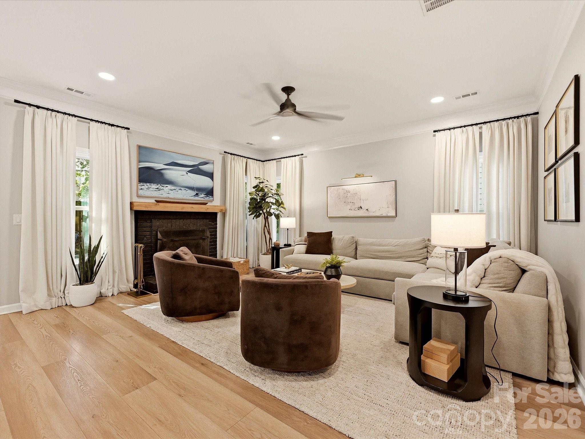 Spacious living room features a wood-burning fireplace, wood-look vinyl plank flooring, abundant natural light, and an inviting open-concept design. - 19706 Valiant Way, Cornelius