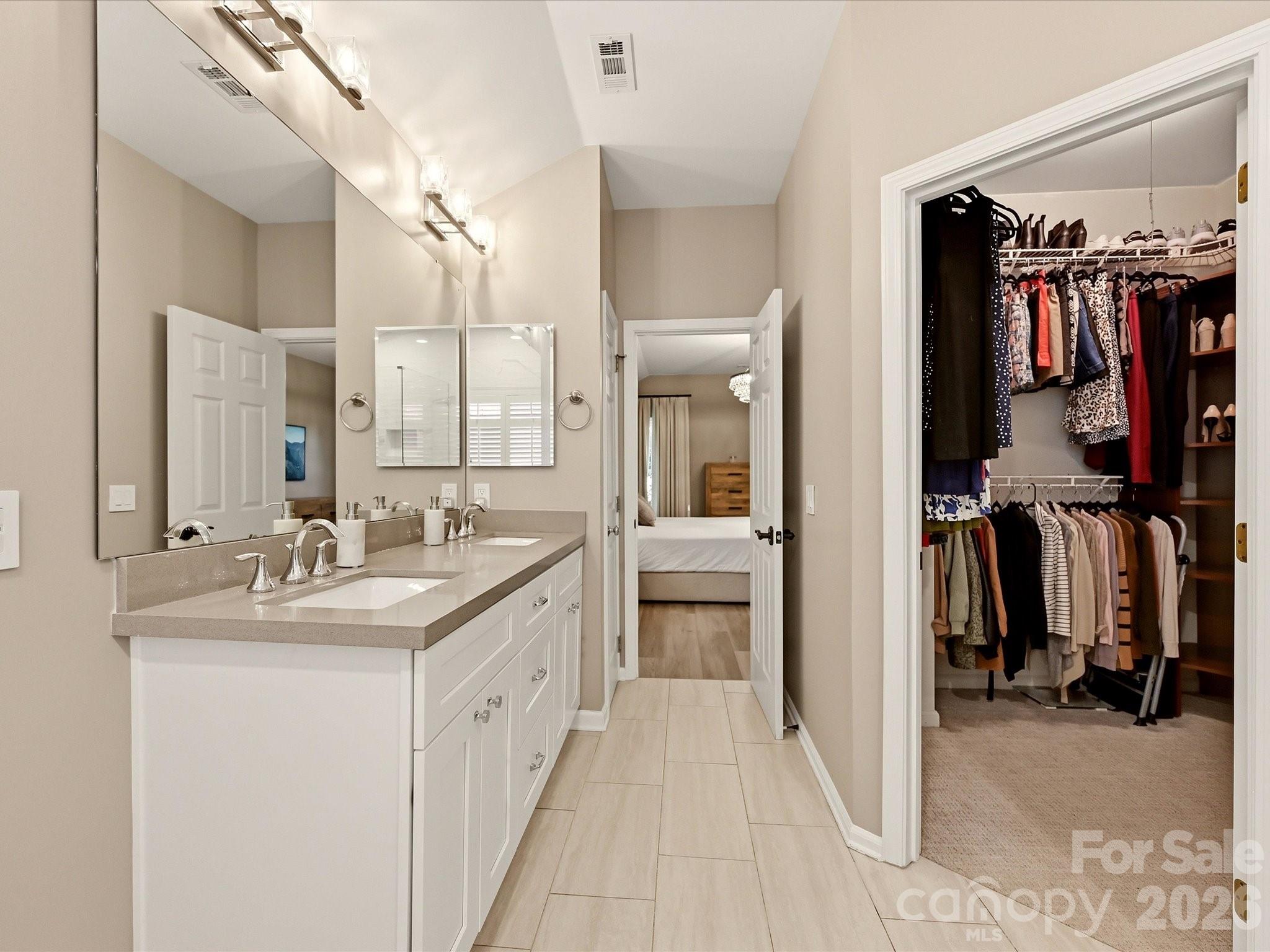 Additional primary bath view highlights the dual vanity, generous storage, and adjoining walk-in closet. - 19706 Valiant Way, Cornelius