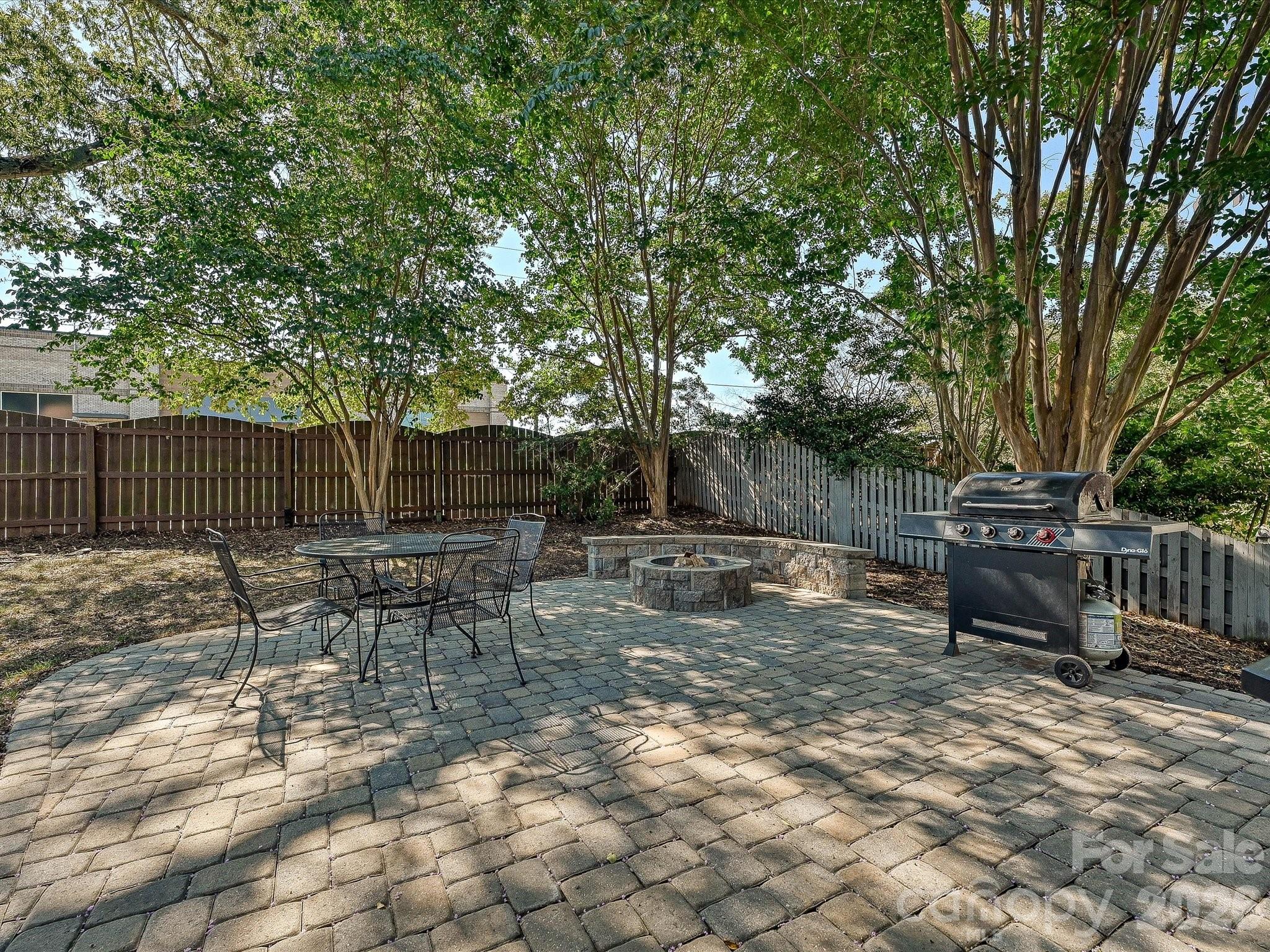 Large backyard patio creates an inviting outdoor entertaining area surrounded by trees and a fenced yard. - 19706 Valiant Way, Cornelius