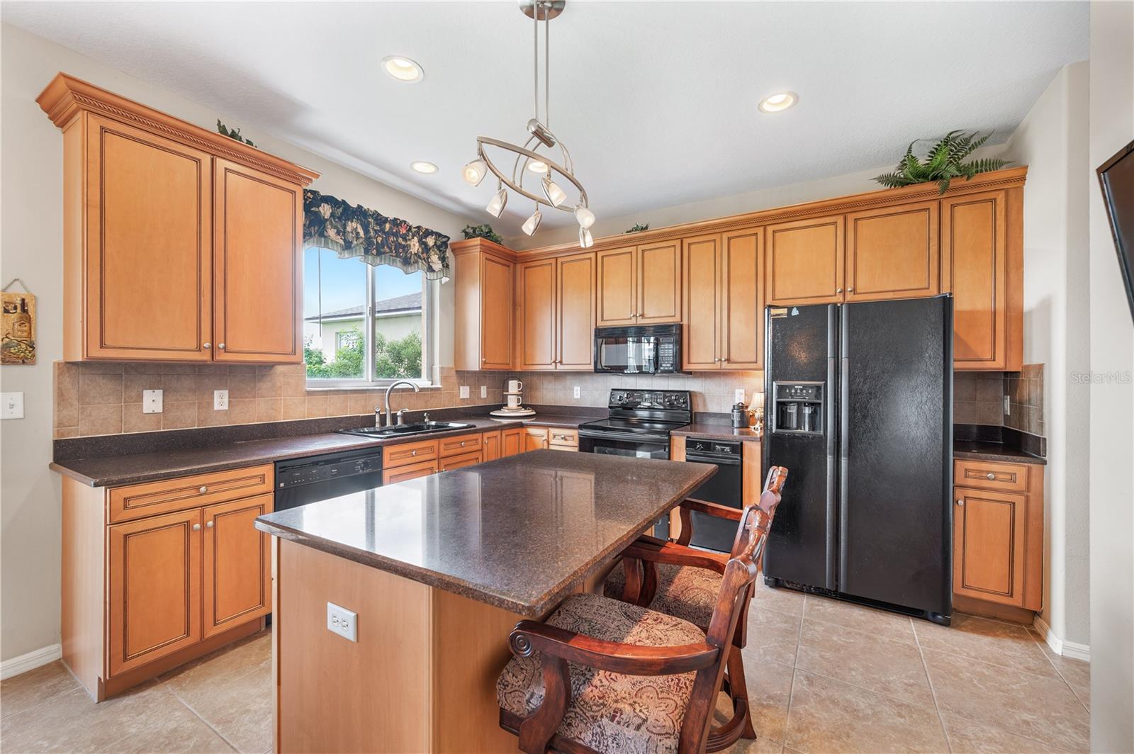 The kitchen is sunny & bright . Surrounded by solid wood cabinetry with plenty of storage , granite countertops, a breakfast Bar , along with a view of Island Lake and the 15th hole - 6937 LAKE EAGLEBROOKE DR, LAKELAND