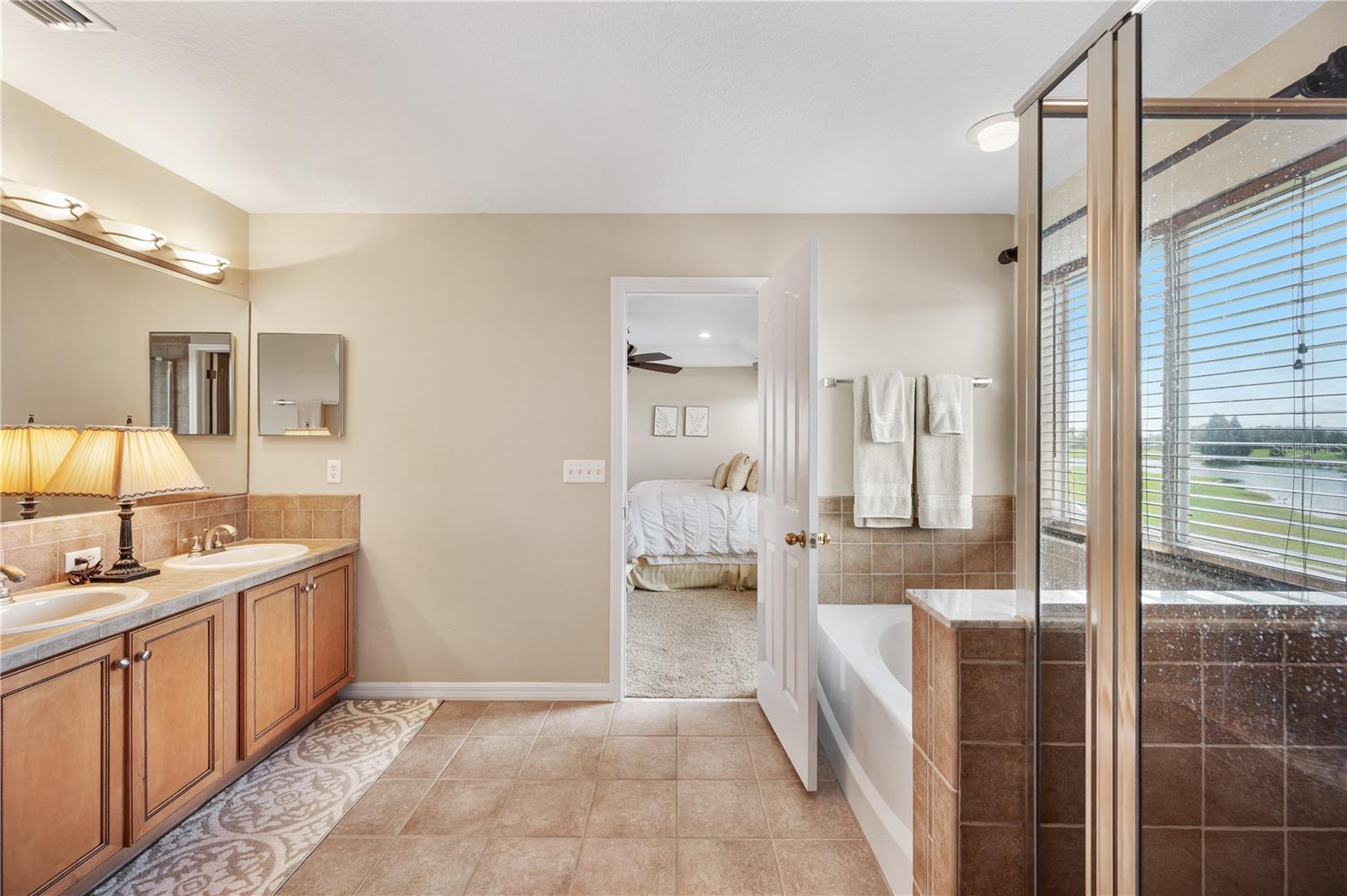 The Primary en-suite bath boasts a large walk in shower , dual vanities, garden jetted tub . - 6937 LAKE EAGLEBROOKE DR, LAKELAND