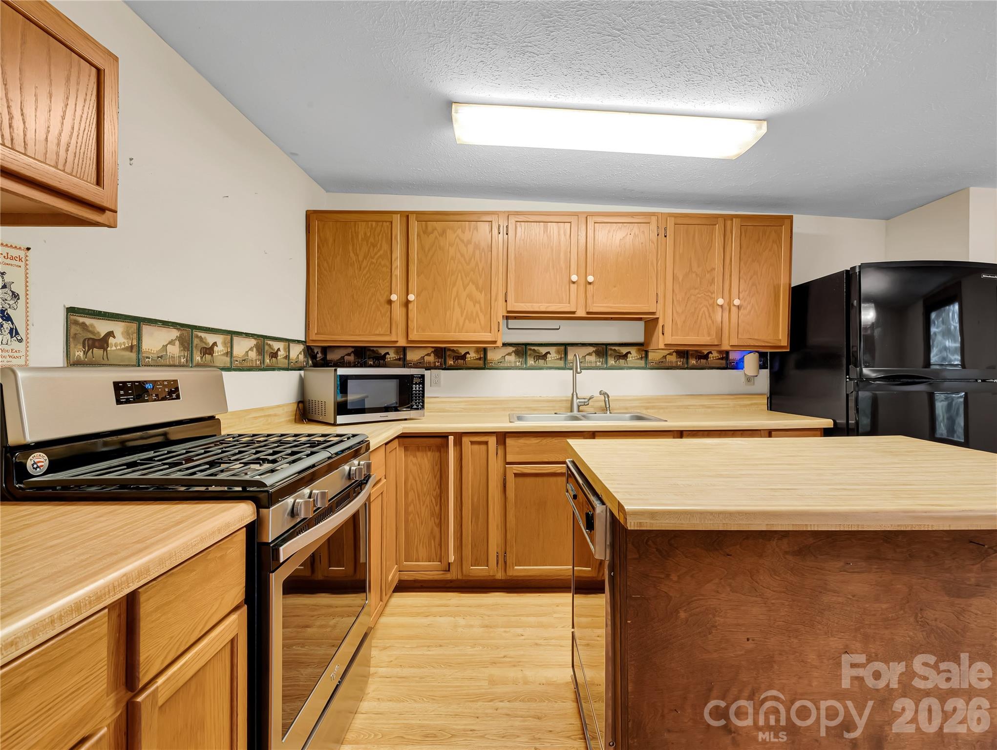 Solid wood cabinets, you can see the slope of the kitchen ceiling if you look at the upper cabinets. Dishwasher is in the kitchen island, gas stove runs on propane. - 989 Fox Mountain Road, Columbus