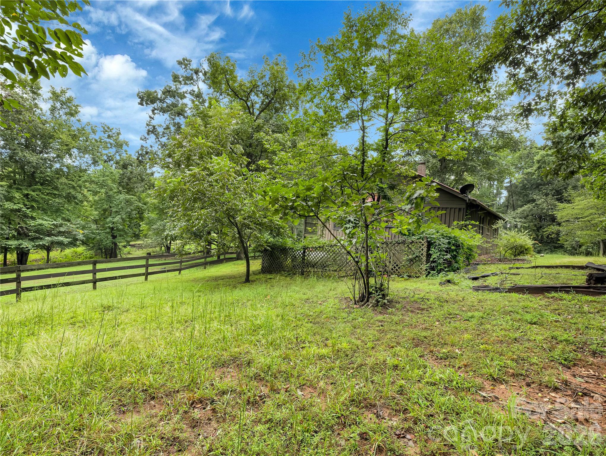 Rear view of the house, there is a dog yard there behind the house with a dog door and small landing and steps down into the dog yard. This fencing needs some attention. - 989 Fox Mountain Road, Columbus