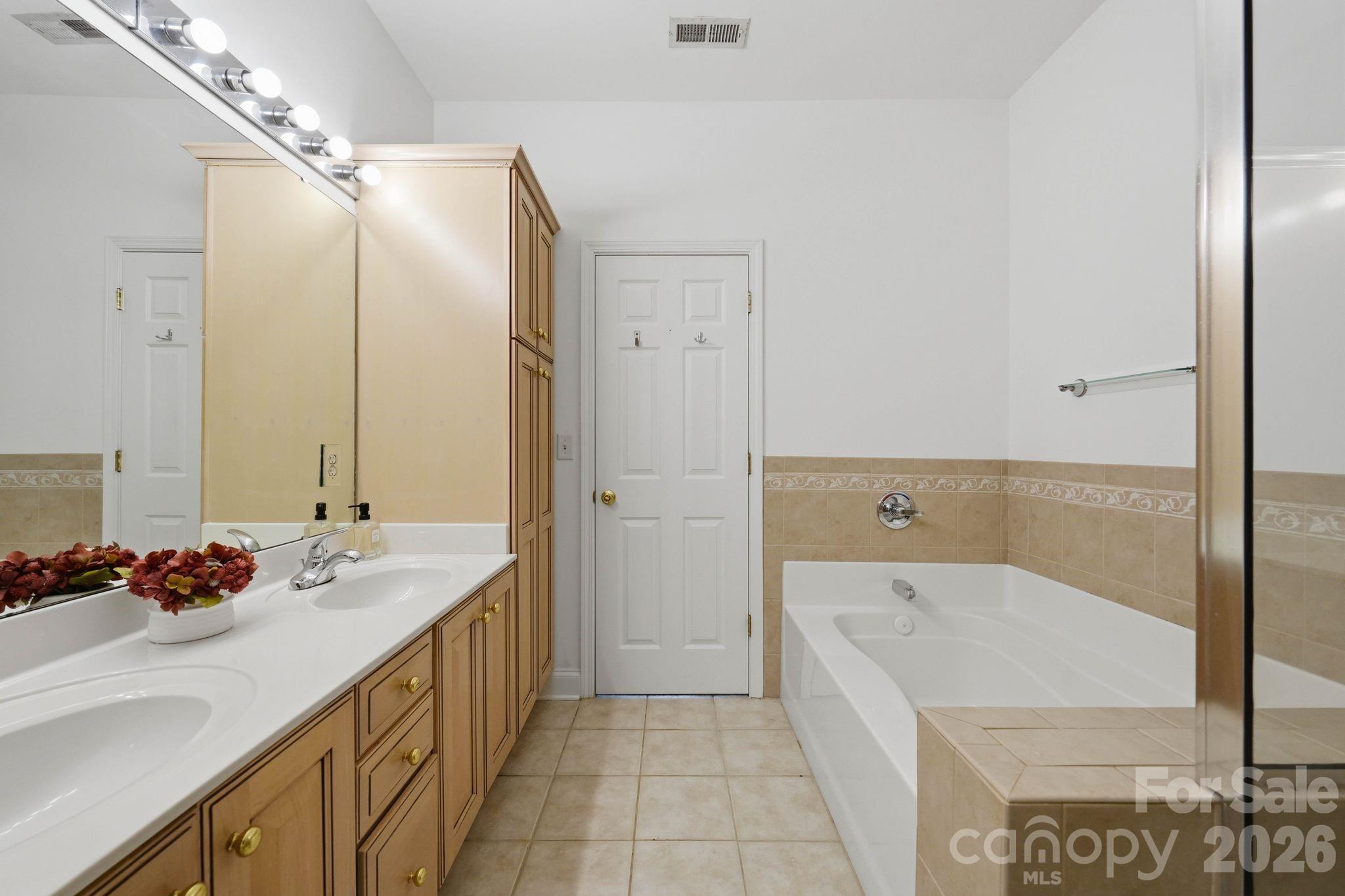 Bright primary bath with dual vanities, garden tub, and a functional layout. - 18810 Cloverstone Circle, Cornelius