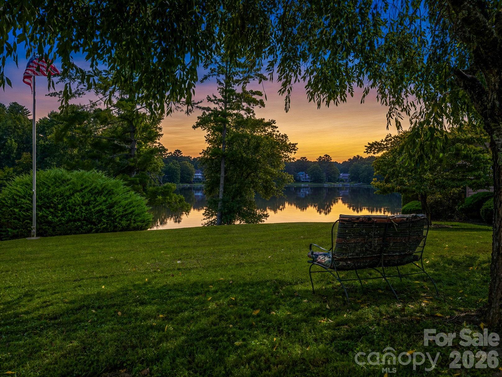 Front yard view of the lake, bench and flag pole convey - 31 Willow Way, Hendersonville