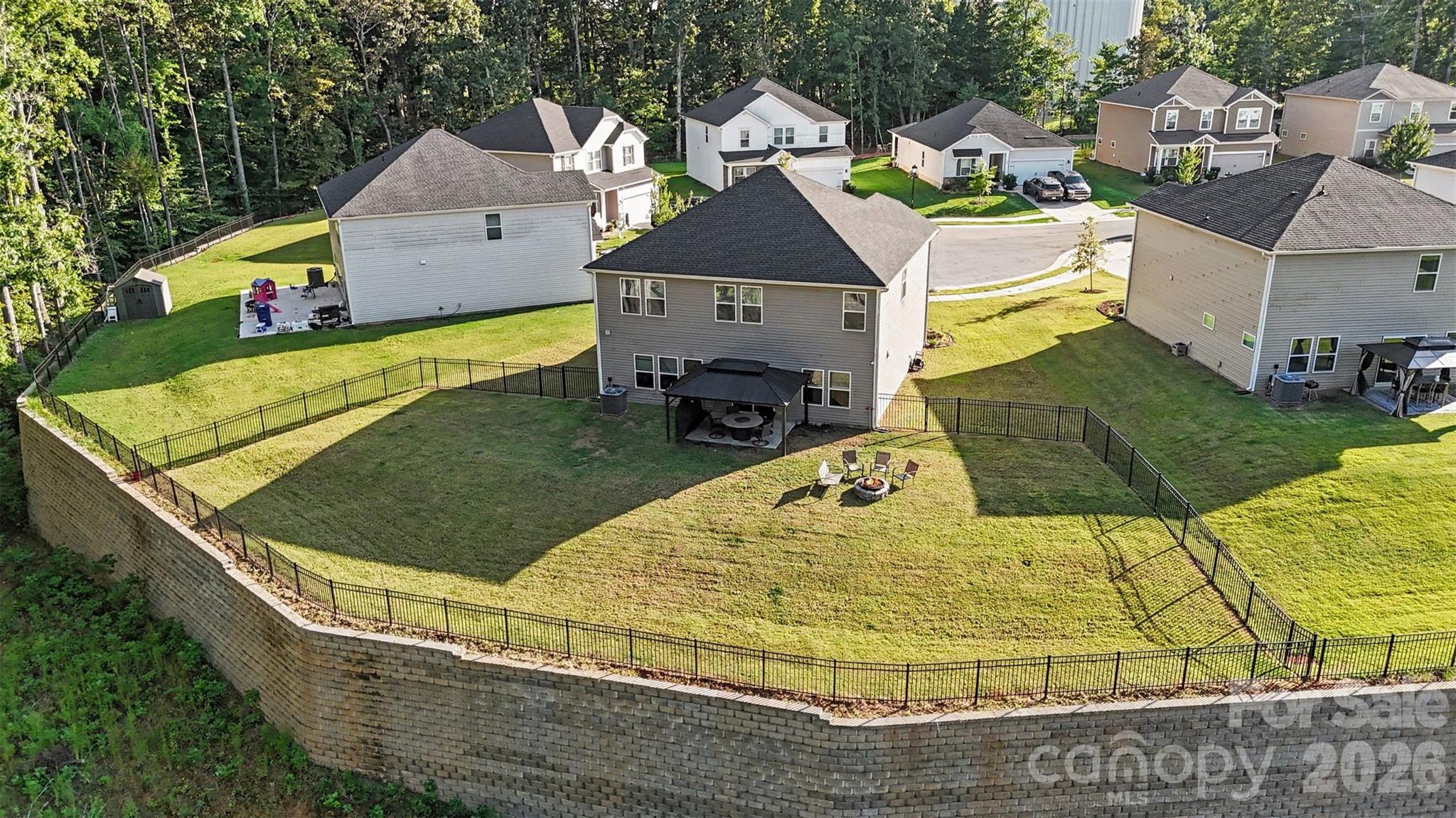 An aerial view of the large, level, fenced backyard. - 1623 Baymont Court, Stanley