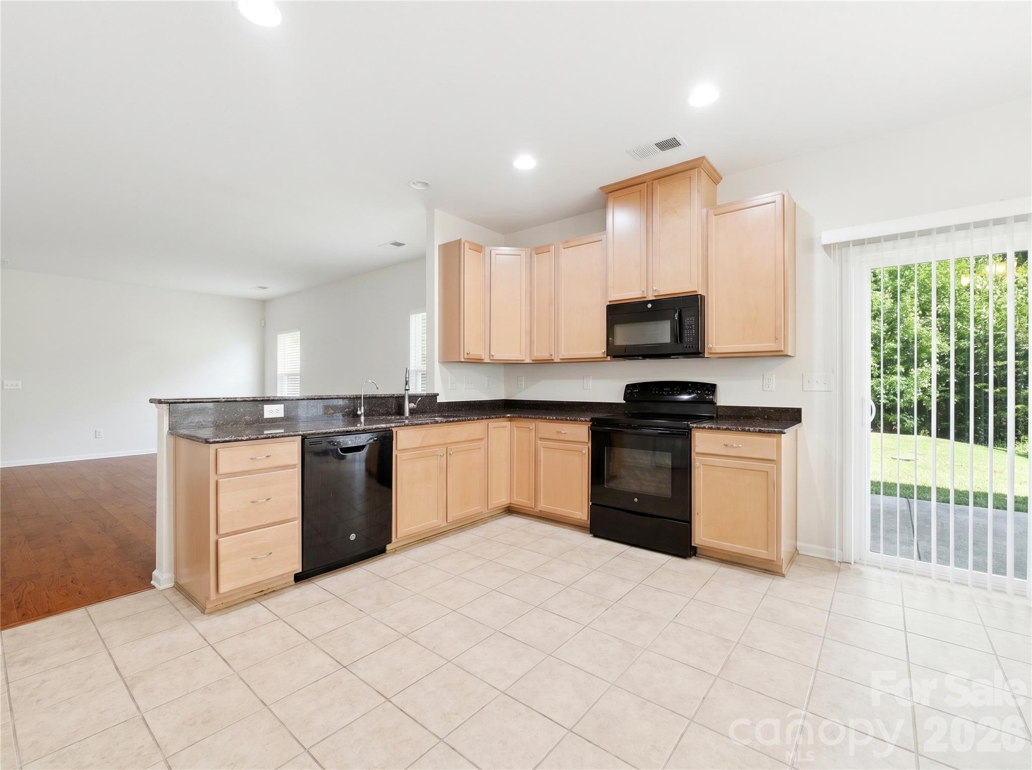 Kitchen: Well-appointed kitchen featuring granite countertops, 42-inch maple cabinetry, recessed lighting, and abundant workspace with direct access to the backyard patio. - 3341 Linetender Drive, Davidson