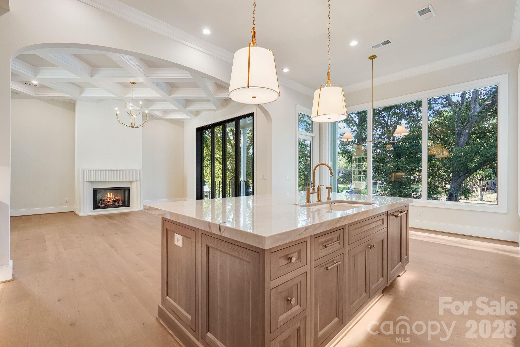 Open sightline from the kitchen into the family room, showcasing the seamless flow of the main level and abundant natural light from expansive windows. - 21216 Rio Oro Drive, Cornelius
