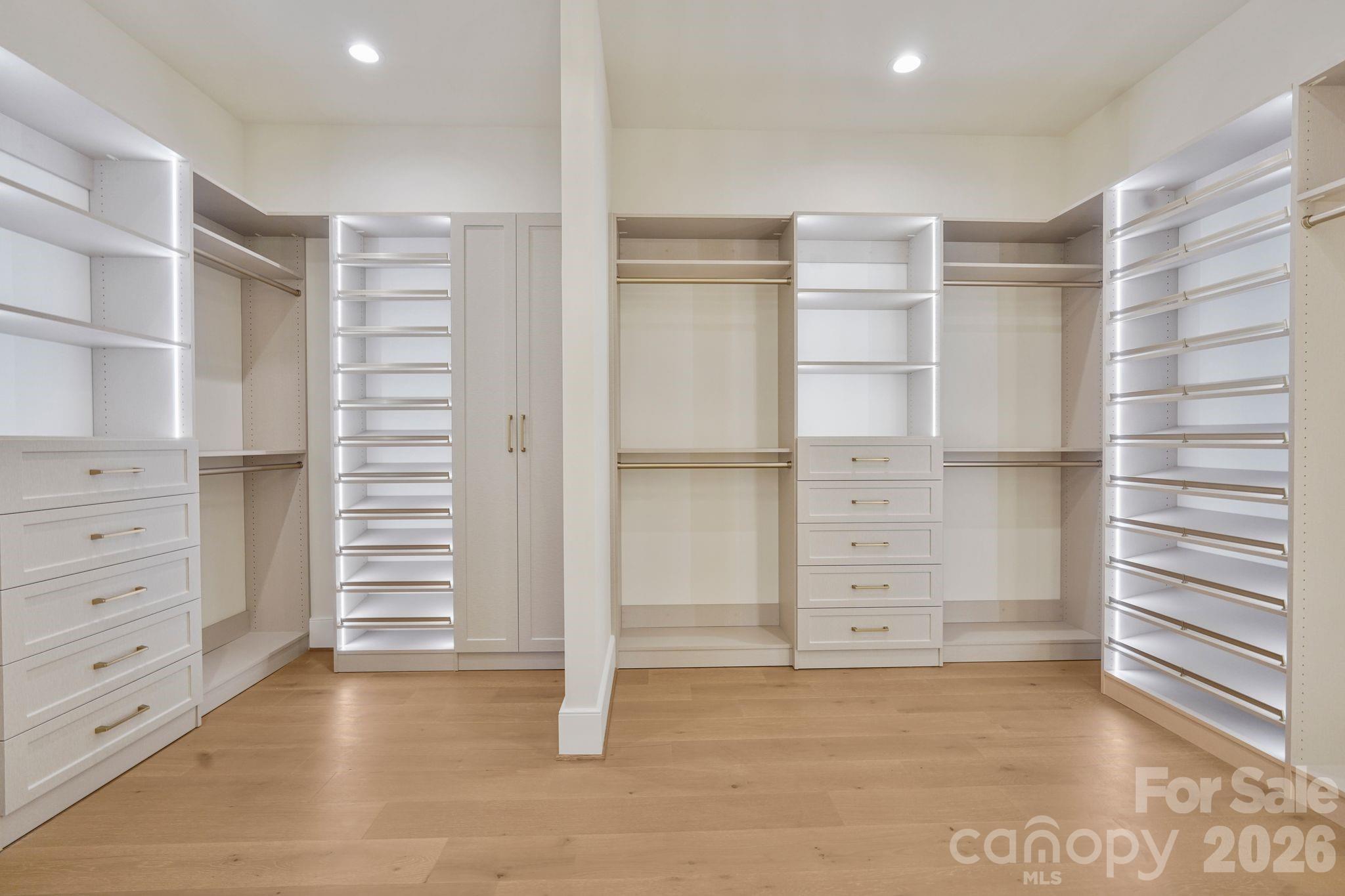 Custom-designed primary closet featuring integrated LED-lit shelving, extensive built-in storage, and a refined boutique-inspired feel. - 21216 Rio Oro Drive, Cornelius