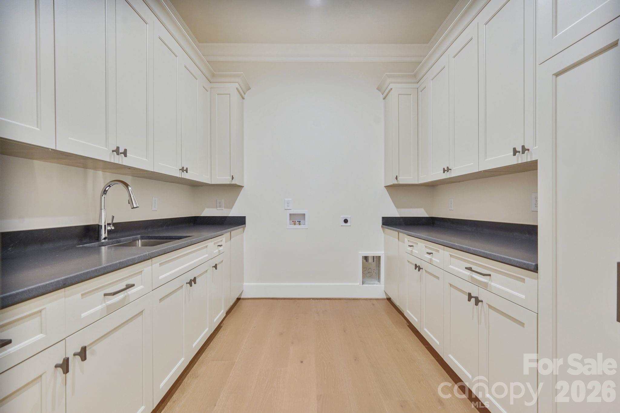 Spacious upstairs laundry room convenient to bedrooms featuring abundant custom cabinetry and storage, thoughtfully finished with a soft-close cavity pocket door for a clean, seamless look. Tons of storage. - 21216 Rio Oro Drive, Cornelius