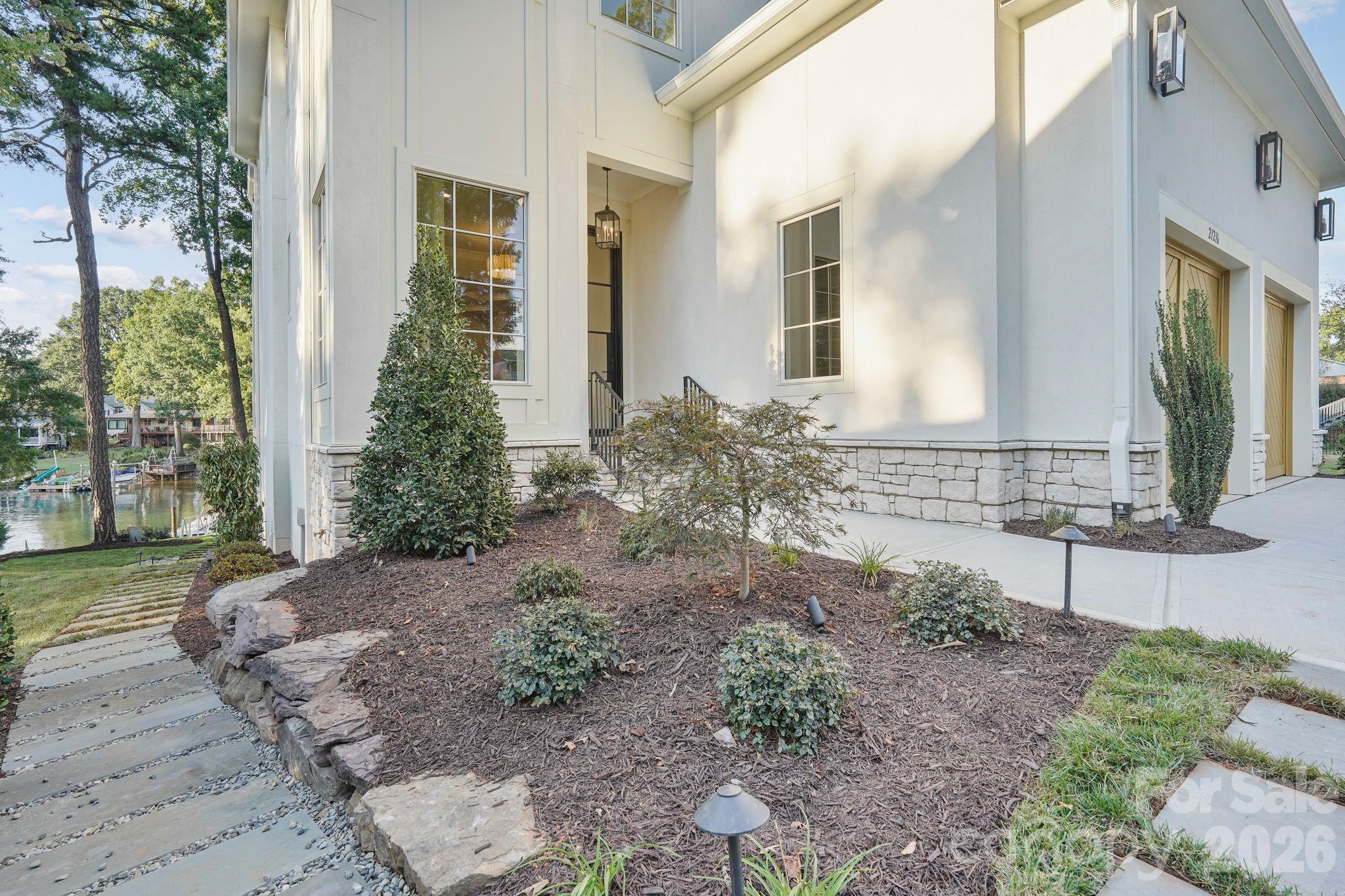 Professionally designed luxury landscaping enhanced by architectural night lighting, beautifully highlighting the home and grounds after sunset - 21216 Rio Oro Drive, Cornelius