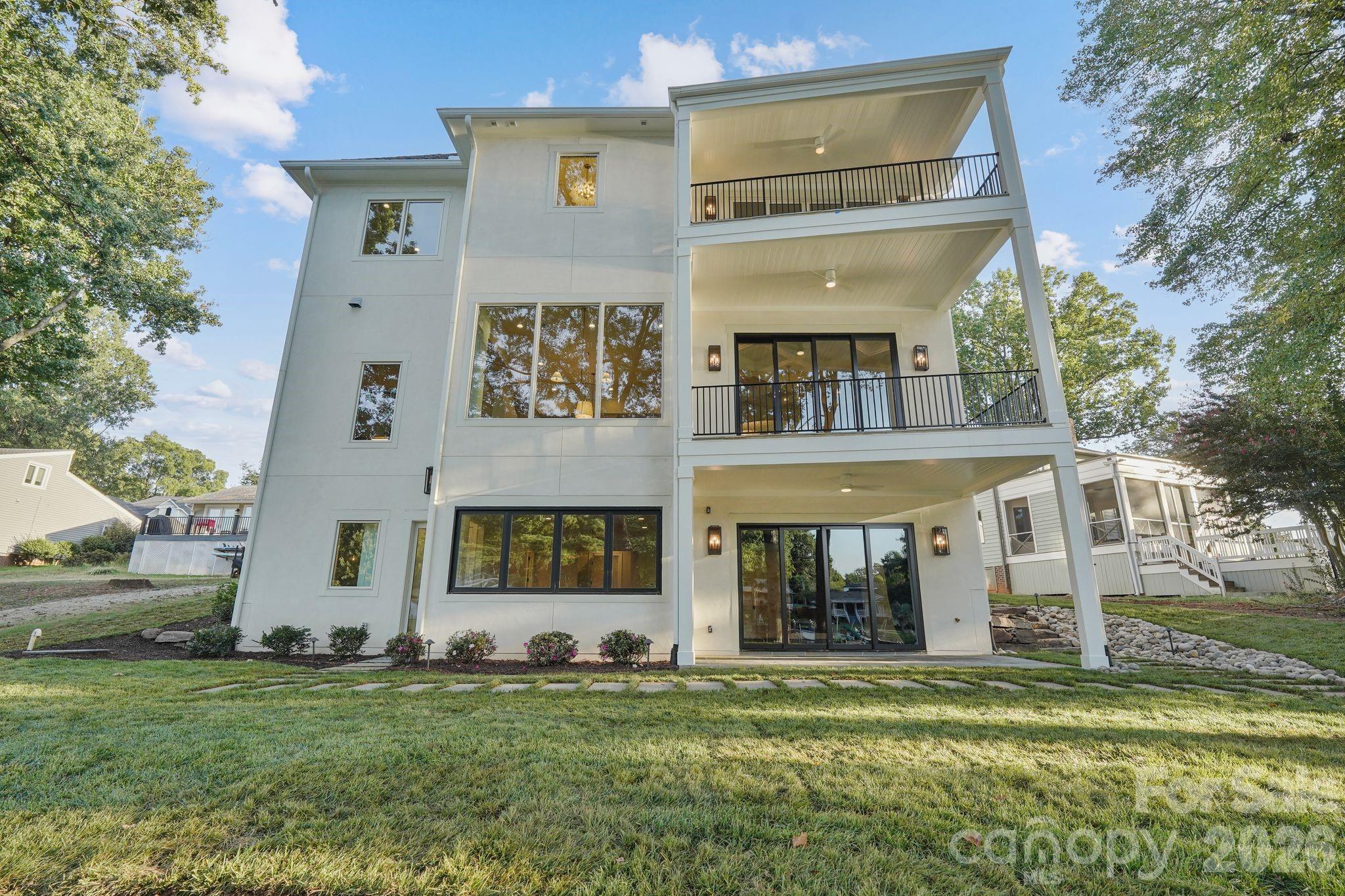 Stunning rear elevation showcasing expansive windows and multiple porches designed to maximize natural light and outdoor living. - 21216 Rio Oro Drive, Cornelius