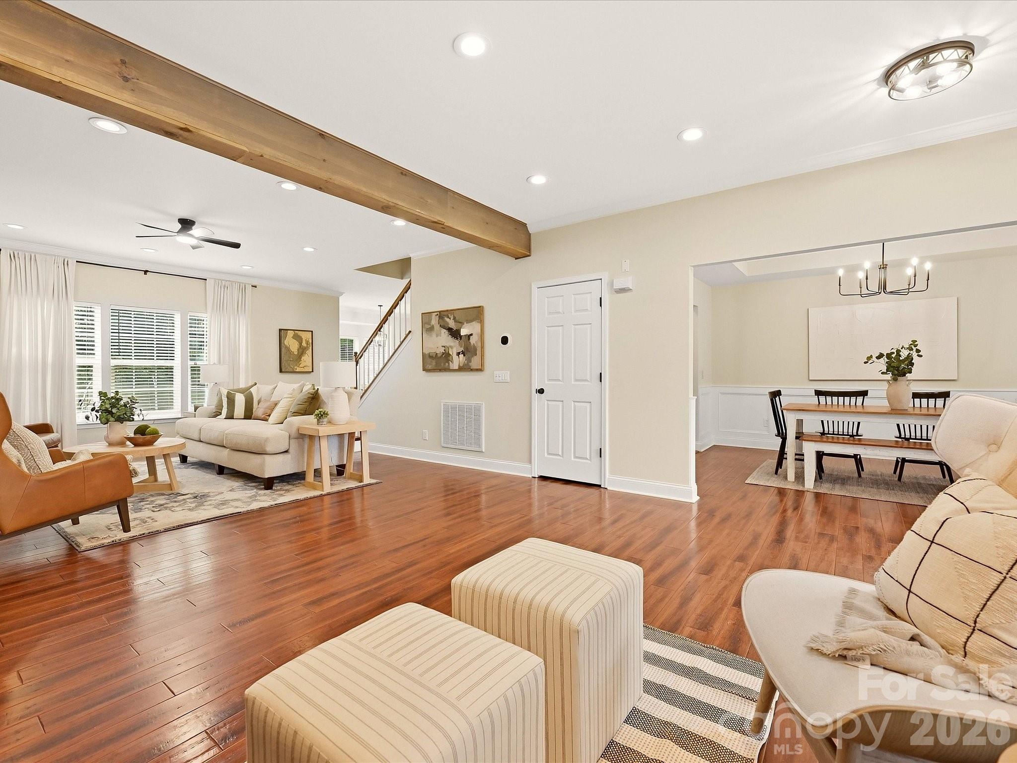 The spacious Great Room features rich wood floors, warm exposed beams, abundant natural light, and an open flow into the adjoining dining space. - 16006 Lavenham Road, Huntersville