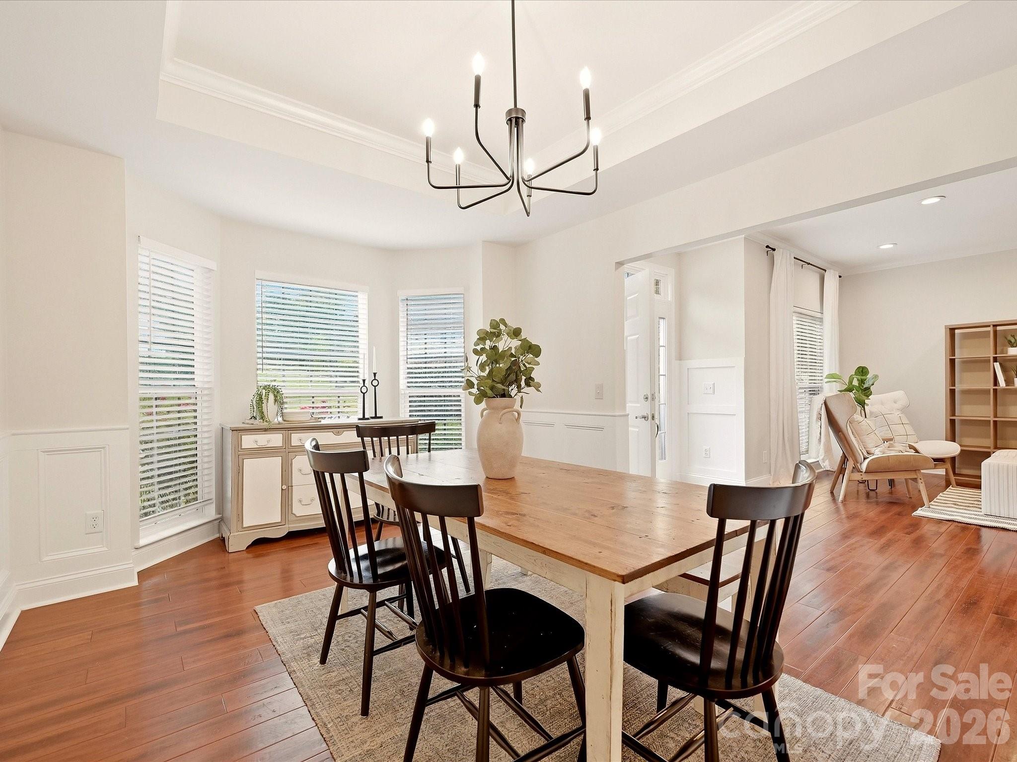 The bright dining room features a tray ceiling, classic wainscoting, a modern chandelier, and abundant natural light for an inviting place to gather. - 16006 Lavenham Road, Huntersville