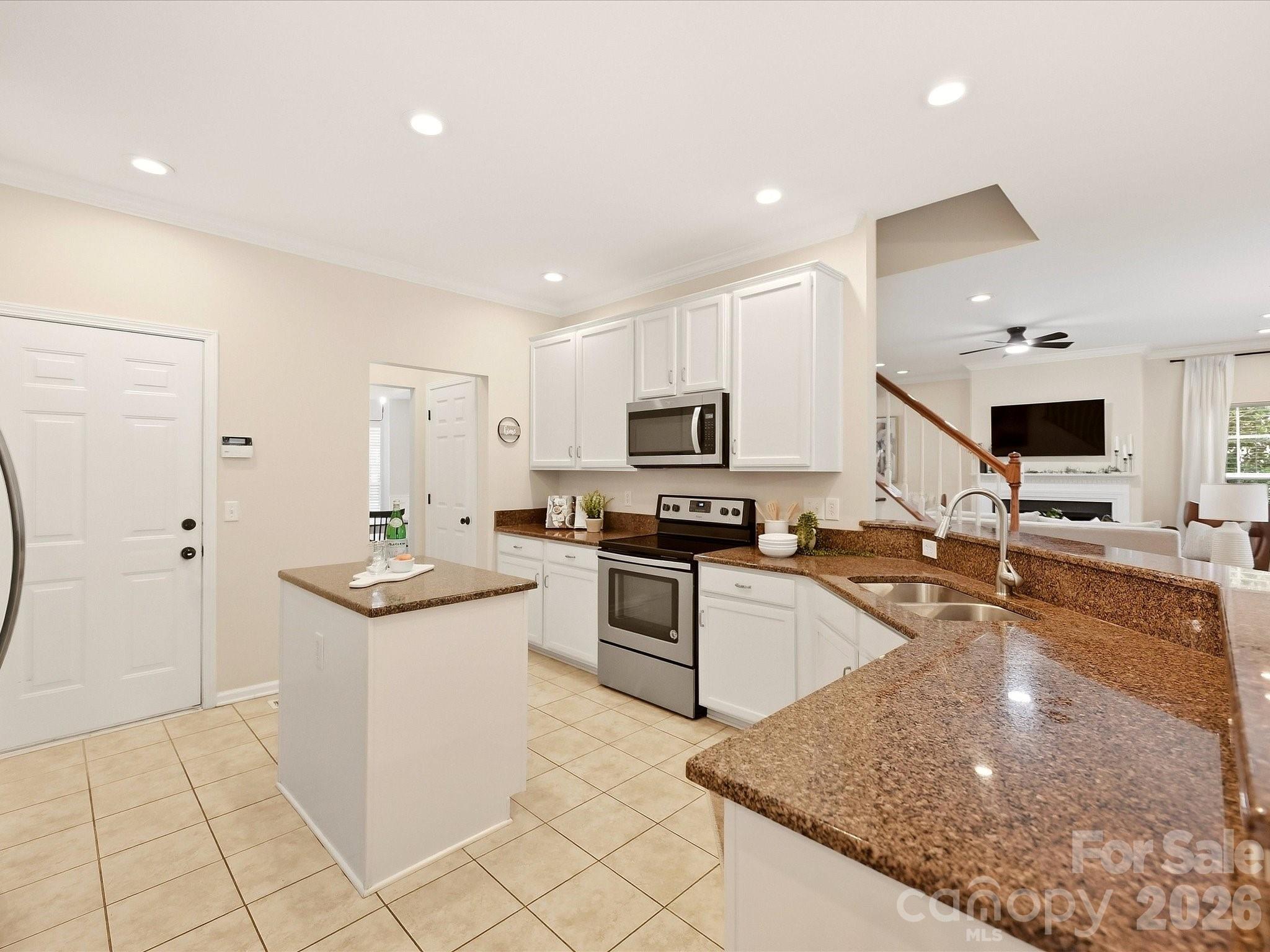 Another view of the bright kitchen highlights the white cabinetry, granite countertops, stainless steel appliances, center island, and open connection to the Great Room. - 16006 Lavenham Road, Huntersville