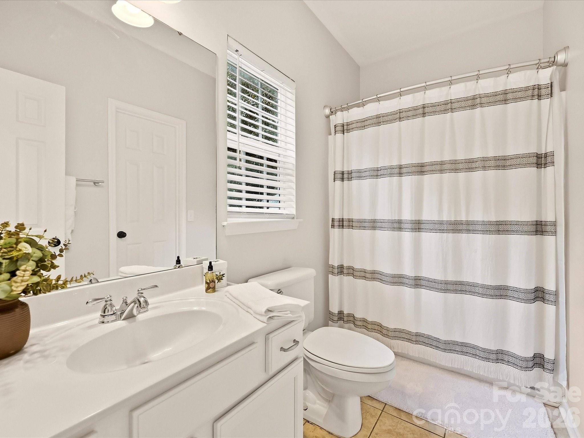 The full bath on main level features a bright, clean design with a spacious vanity, tub/shower combination, and natural light from the window. - 16006 Lavenham Road, Huntersville