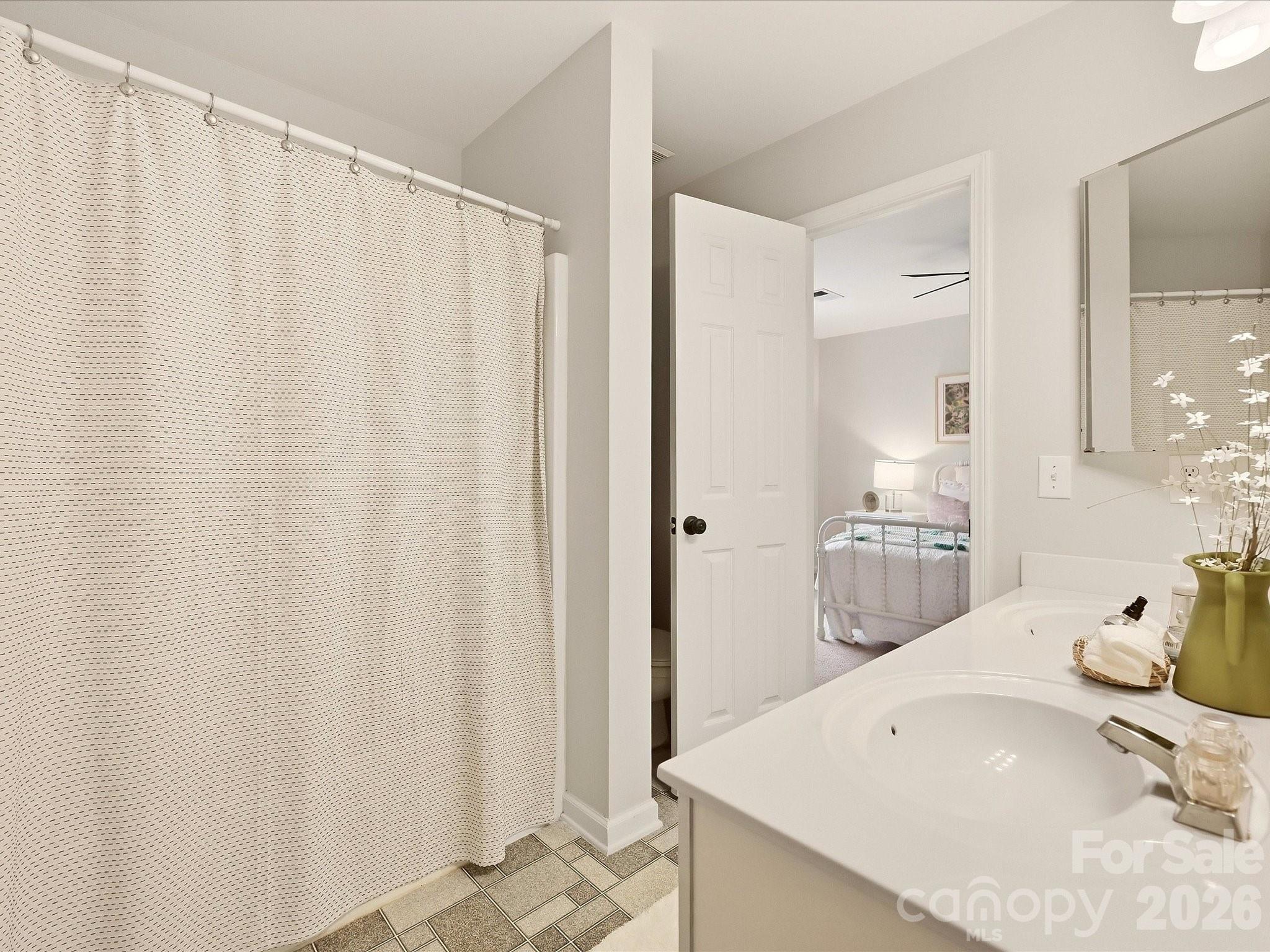 The Jack-and-Jill bath features a dual-sink vanity, tub/shower combination, and convenient access between two bedrooms for easy everyday functionality. - 16006 Lavenham Road, Huntersville