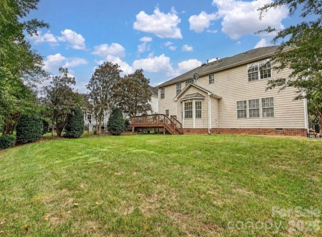 The spacious backyard offers a peaceful, tree-lined setting with a large lawn and easy access to the elevated back deck. - 16006 Lavenham Road, Huntersville