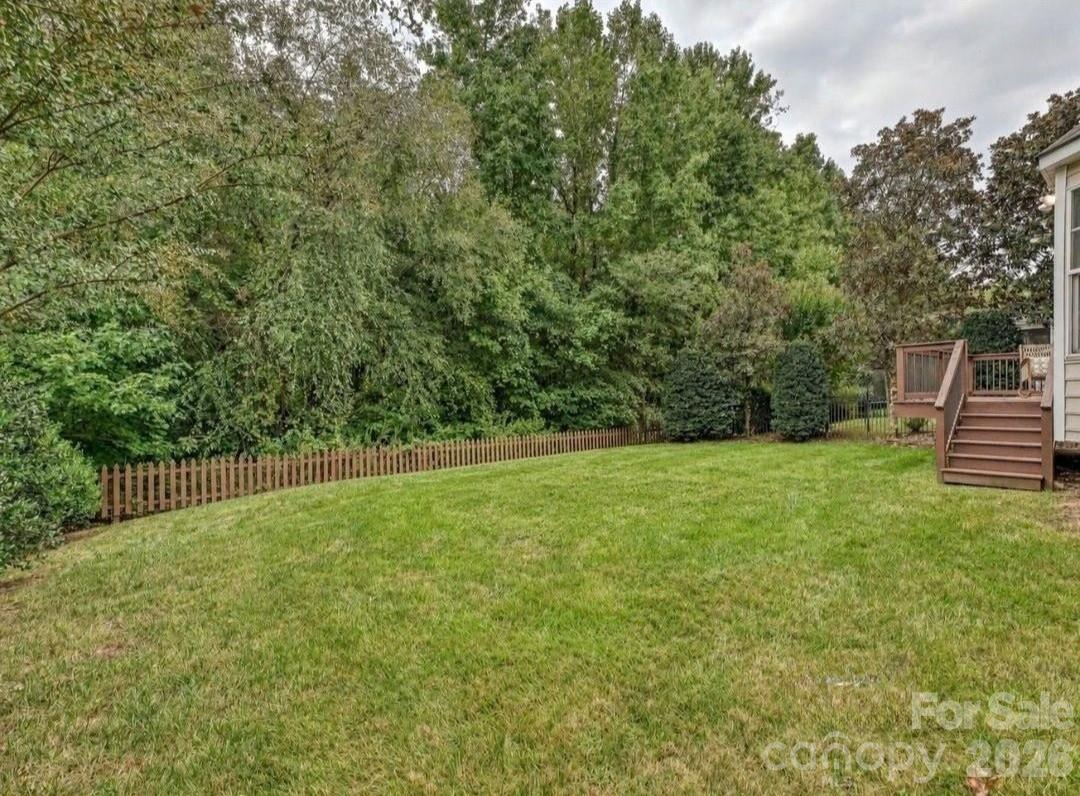 The spacious backyard offers a peaceful, tree-lined setting with a large lawn and easy access to the elevated back deck. - 16006 Lavenham Road, Huntersville