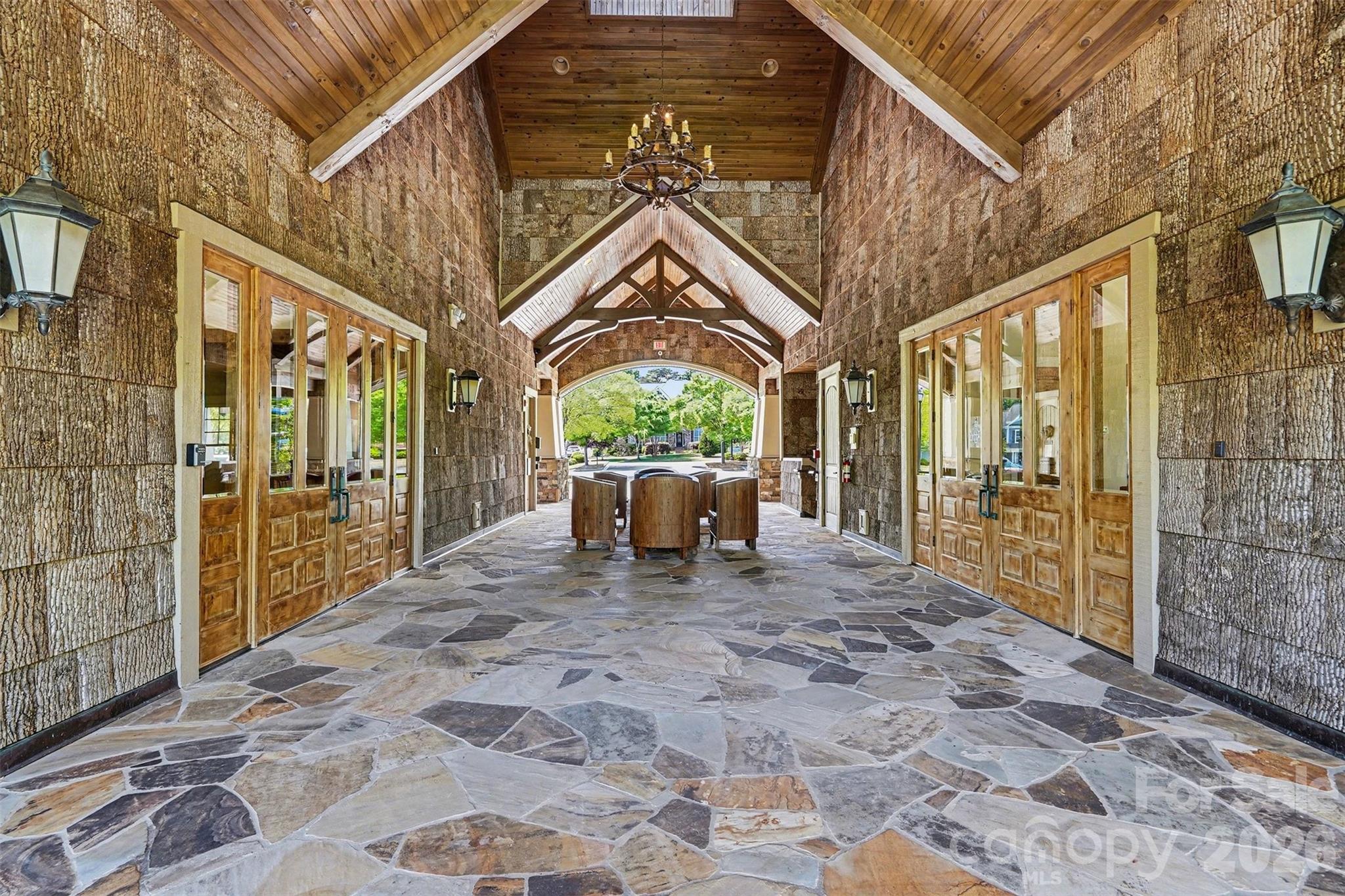 This covered entry to the clubhouse has stone floors, timber beams, and a lantern chandelier. It has a cozy lodge feel. - 8027 Longwaters Court, York