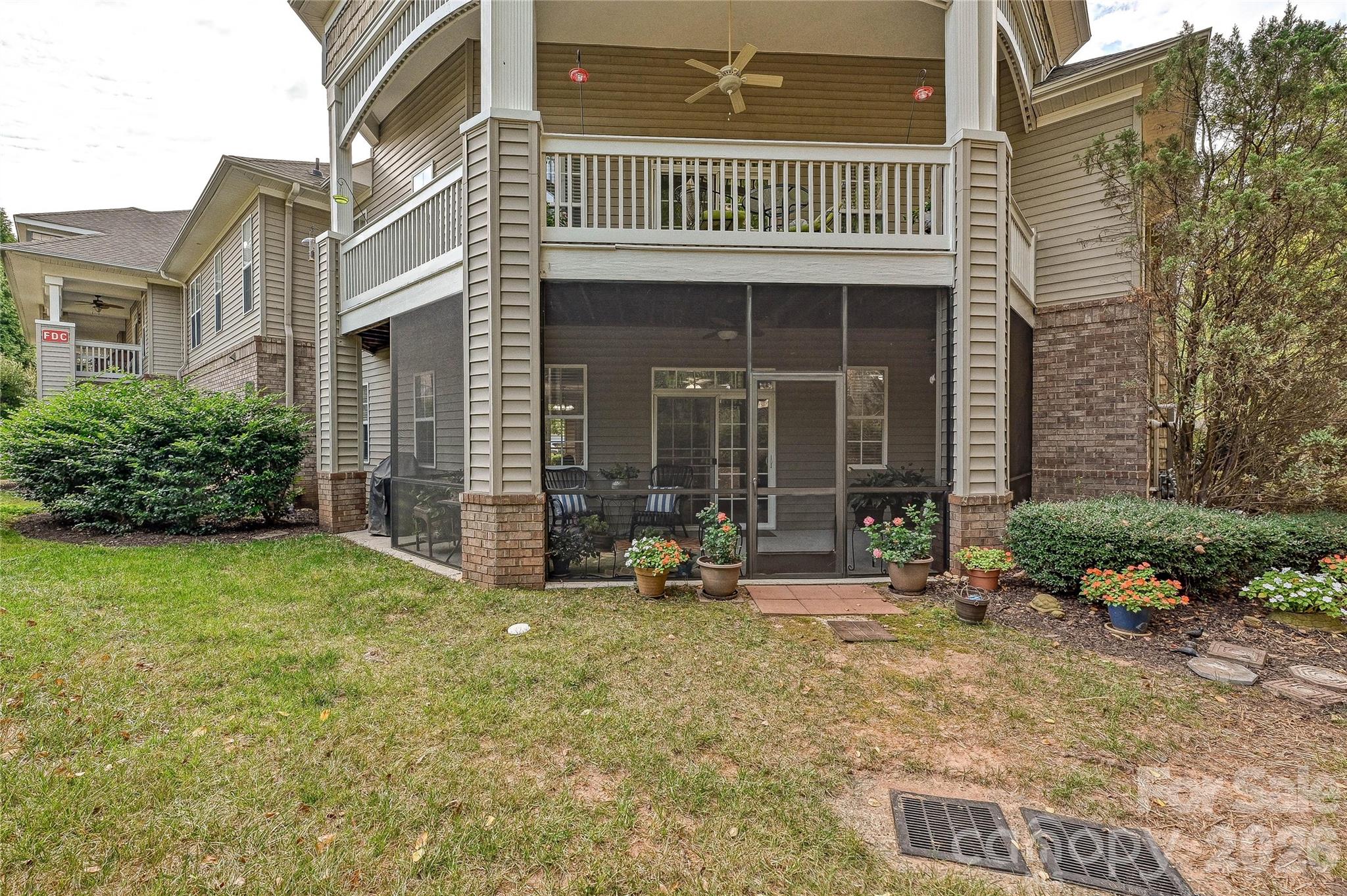 Rear exterior view highlights the ground-level end-unit location, covered screened porch, and established Edinburgh Square setting. - 9009 Rosalyn Glen Road, Cornelius