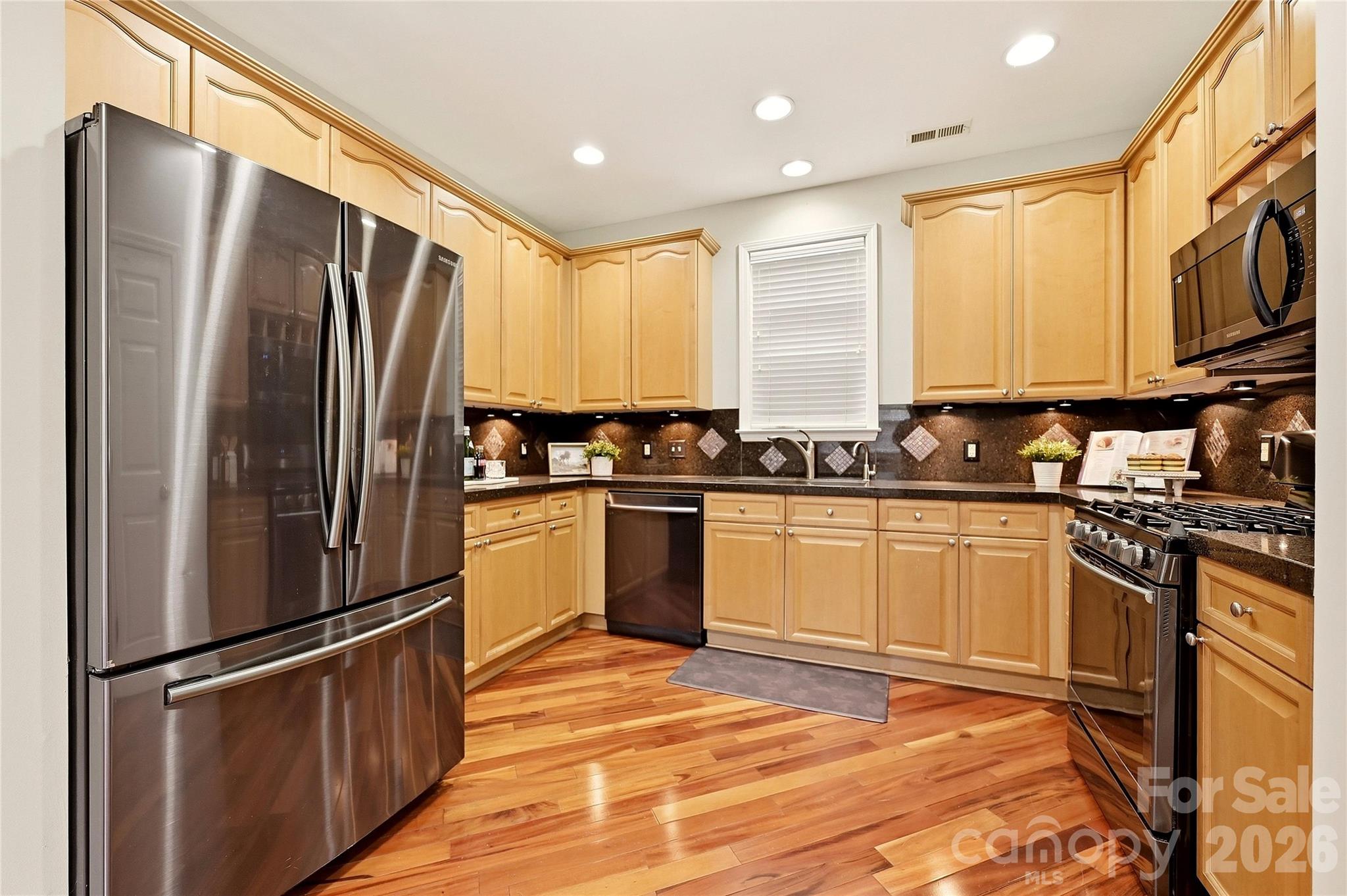 Spacious kitchen features hardwood flooring, generous cabinetry, stainless steel appliances, and ample counter space. - 9009 Rosalyn Glen Road, Cornelius