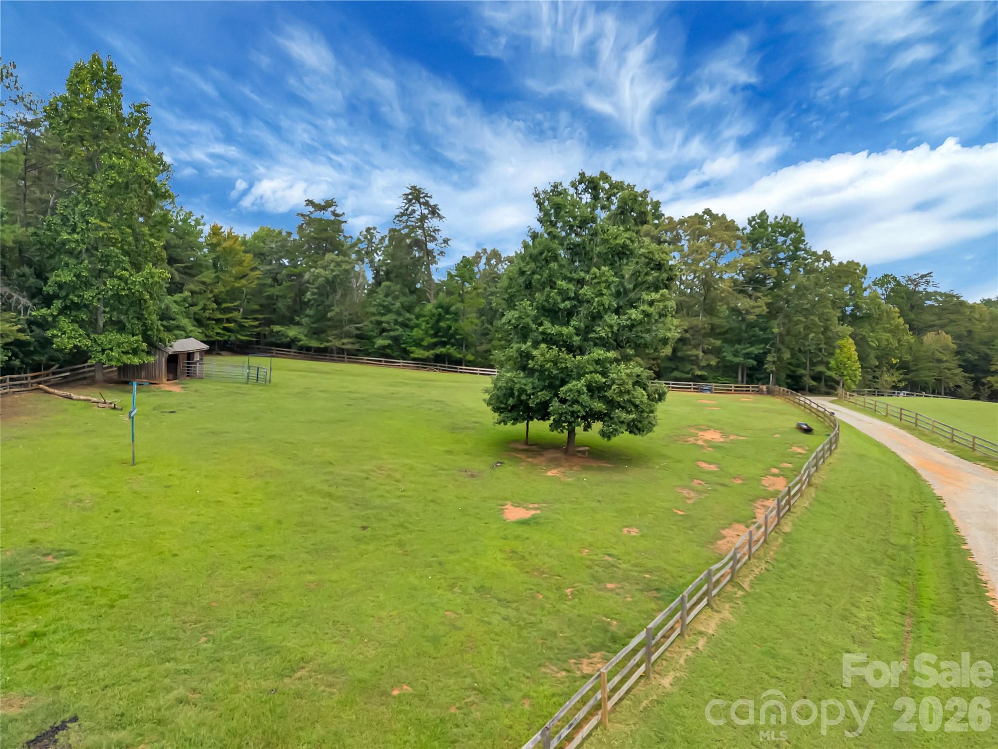 Established pasture with 3 board fencing backed with wire mesh for safety. Really nice run in shed/barn makes this space perfect for horses or livestock. - 27 & 56 Troy Lane, Tryon