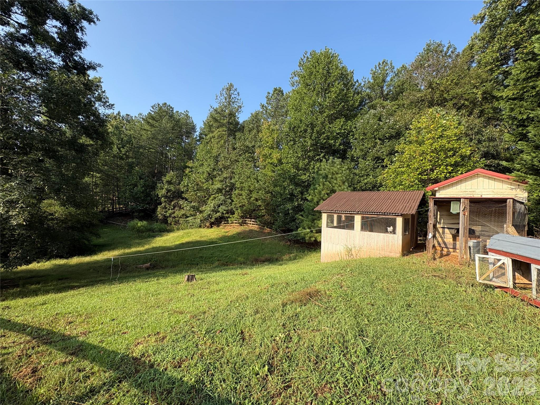 There is a small fenced paddock behind the guest house, with a large chicken coop and extra storage building or animal shelter. - 27 & 56 Troy Lane, Tryon