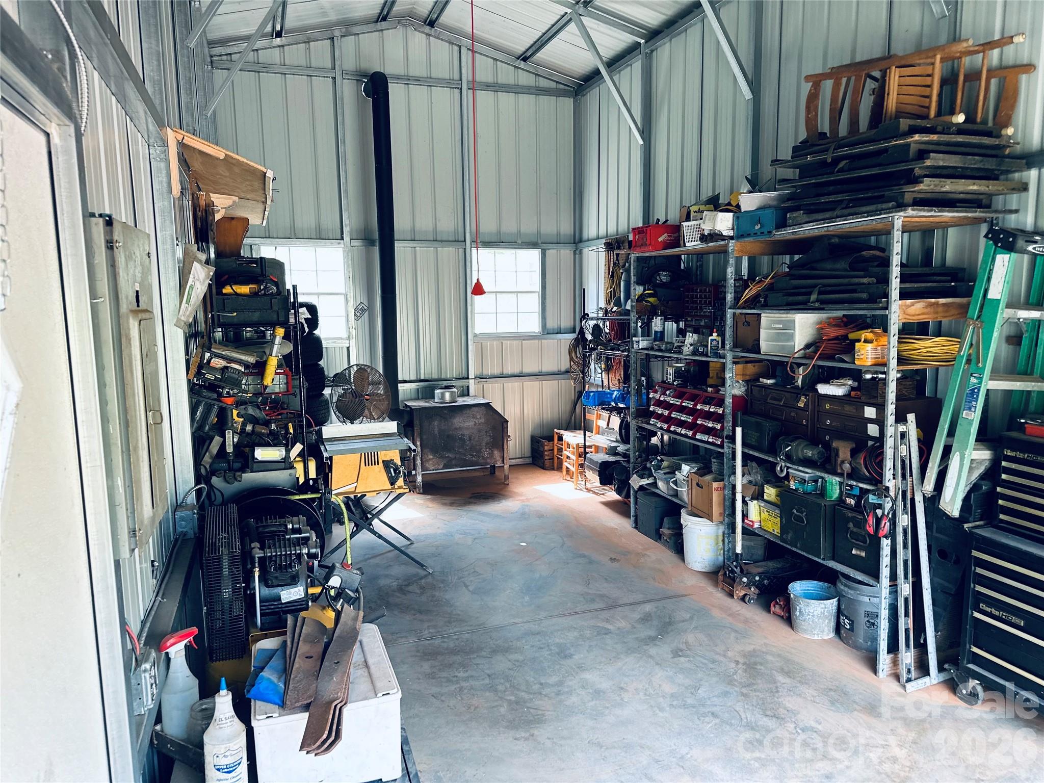 This garage/workshop in the metal building measures 25'x11'8" with a wood stove and concrete slab floor. The electric service for this building runs off of a generator. Door opening is 12' high and 10' wide. Two side doors for easy access. - 27 & 56 Troy Lane, Tryon