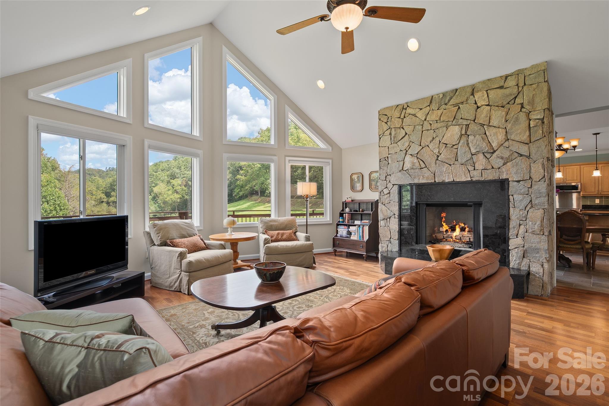 Dramatic vaulted great room with soaring windows, hardwood flooring and impressive stone fireplace. - 174b Marina Cove, Waynesville