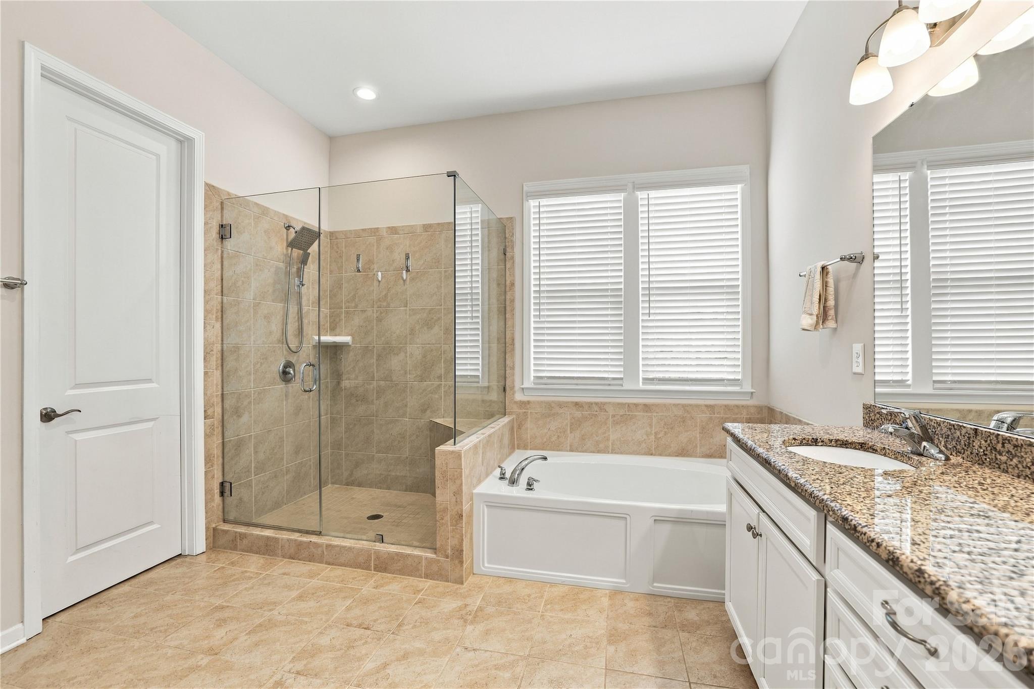 Primary bath features large frameless walk-in shower, soaking tub, double sink vanity, generous counter and storage space, private WC, walk-in closet. - 8504 Hope Run Court, Indian Land