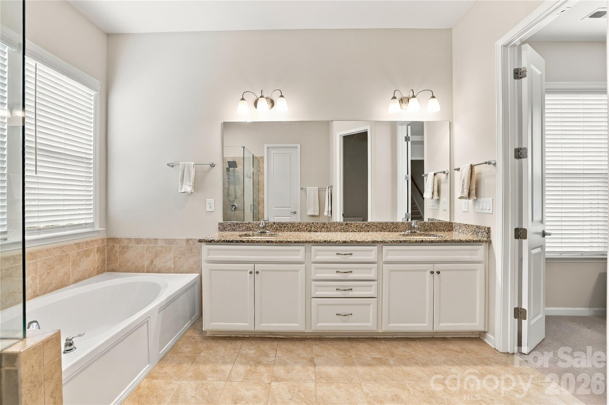 Primary bath: granite vanity counter, crisp white cabinetry, tile flooring and surround give the room a crisp, clean look. Picture window provides excellent natural light. - 8504 Hope Run Court, Indian Land