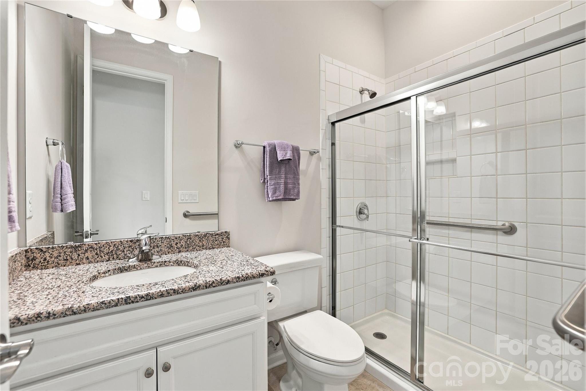 Bathroom serving the home's two front bedrooms. Expanded step-in shower with tile surround, grab bars, granite vanity top, tile floor. Also serves as a powder room. - 8504 Hope Run Court, Indian Land