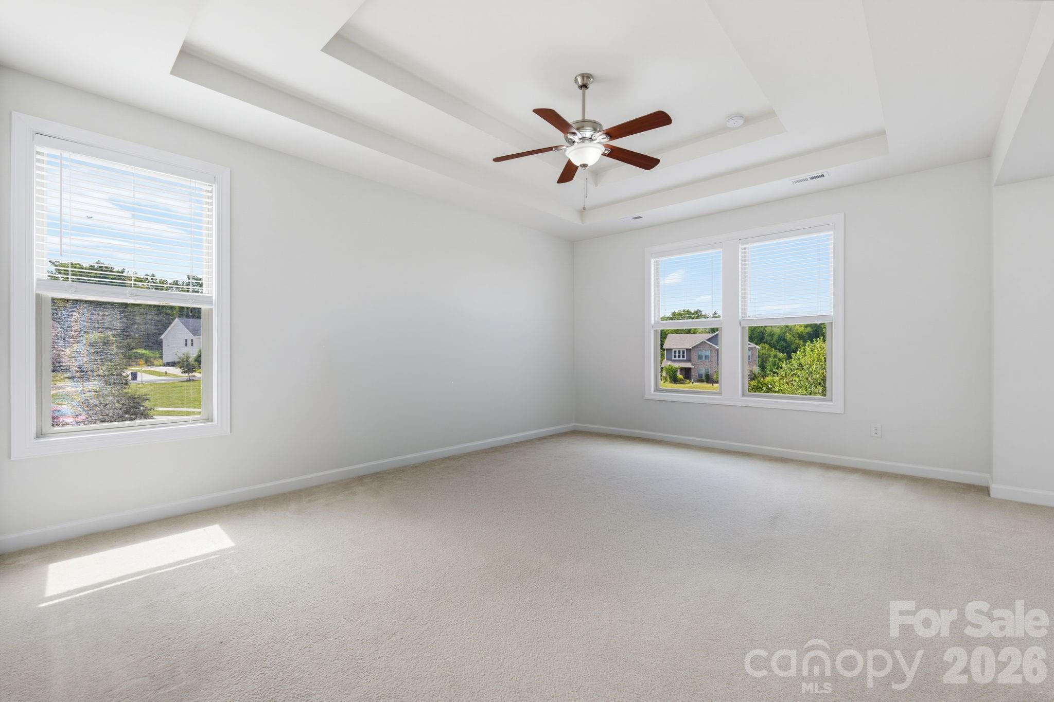The oversized primary bedroom features a tray ceiling, multiple windows, and the peaceful scale of a true private retreat. - 8315 Breton Way, Harrisburg