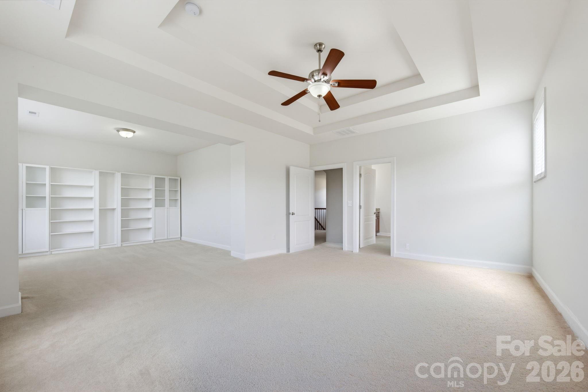 The primary suite extends into a generous lounge with custom built-in shelving, offering room to unwind beyond the sleeping area - 8315 Breton Way, Harrisburg