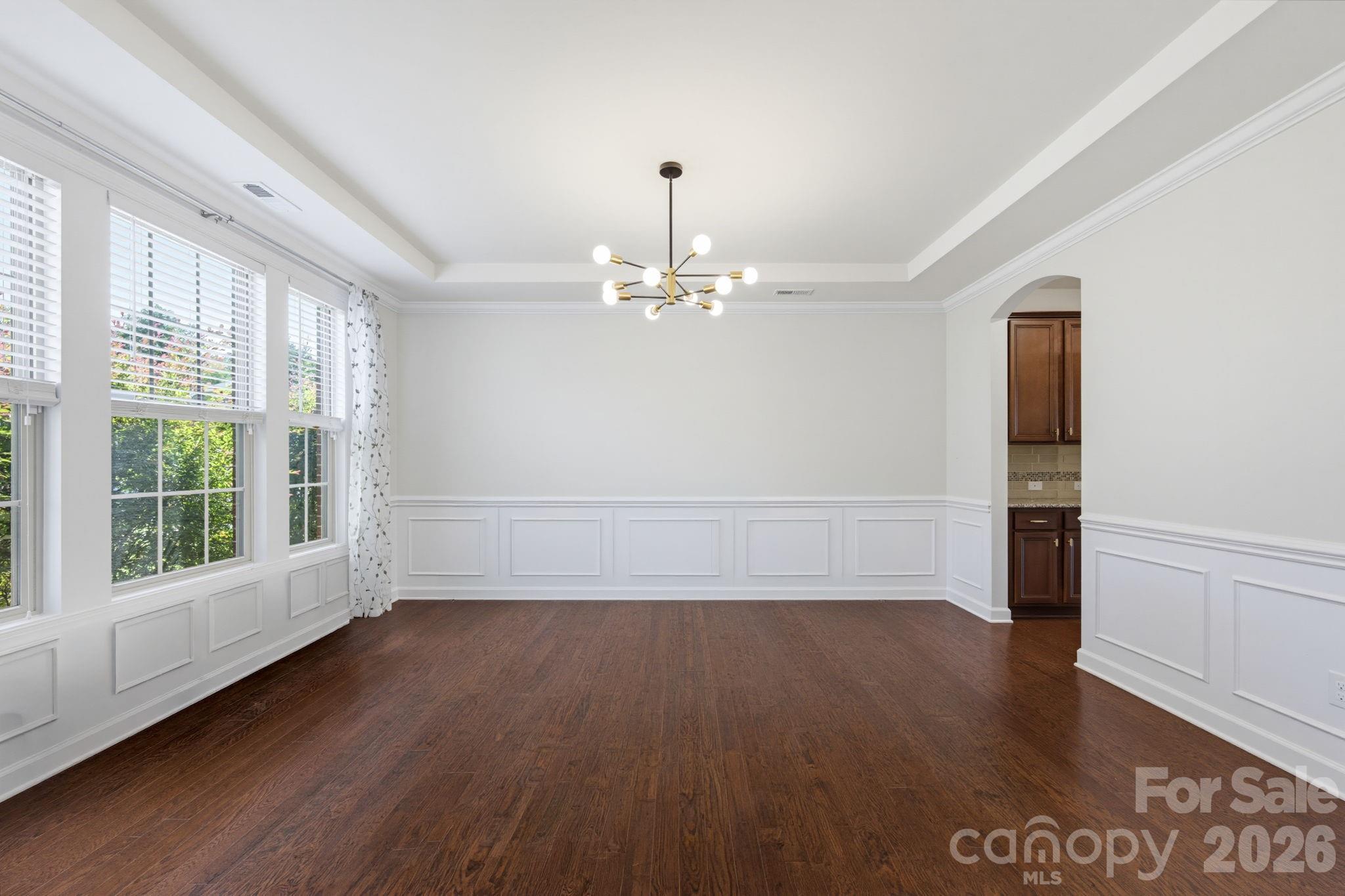 The formal dining room pairs tray-ceiling detail and classic wainscoting with generous windows for a bright, polished setting. - 8315 Breton Way, Harrisburg