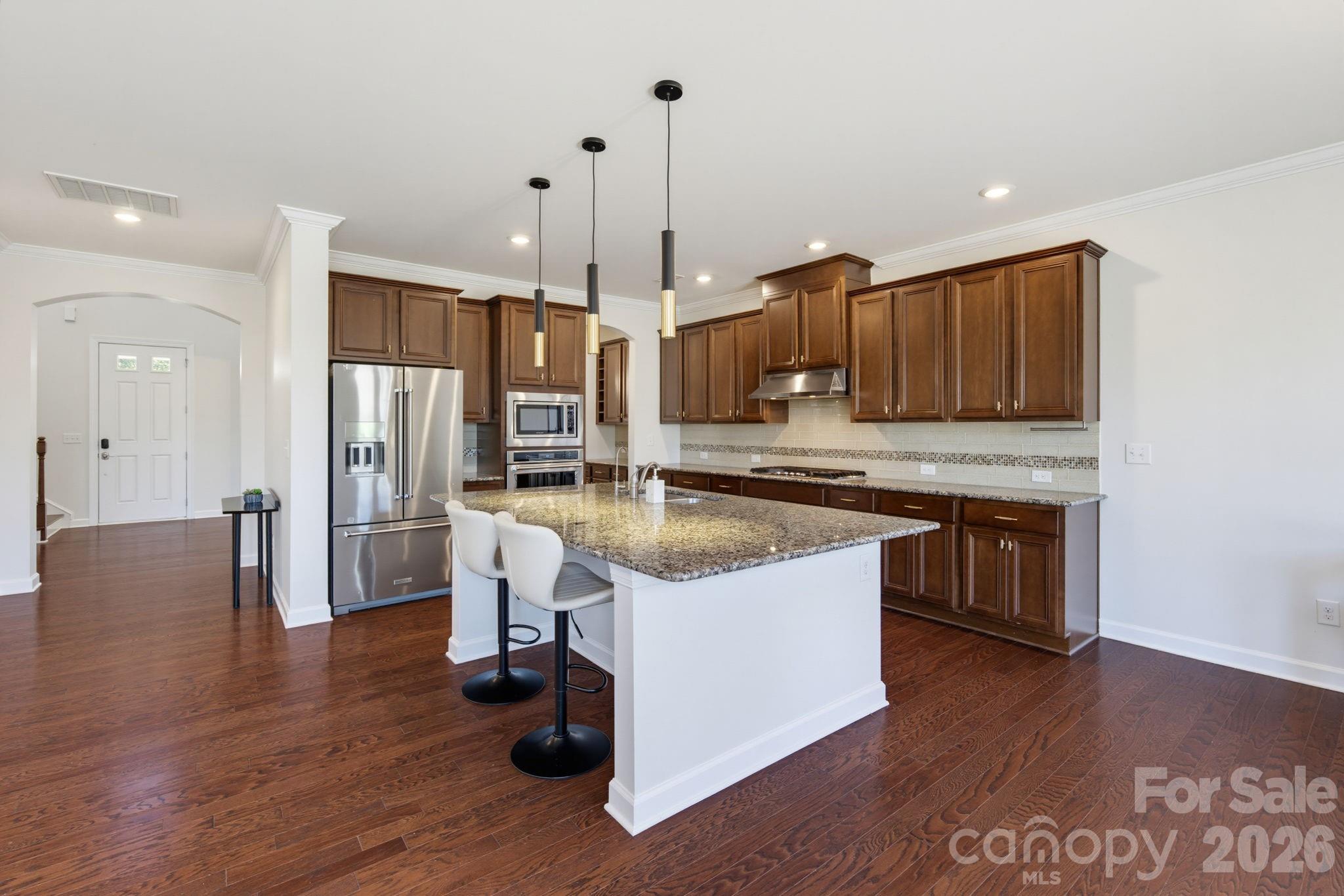 A broad view of the kitchen highlights the central island, updated pendant lighting, and generous storage that keep your life organized - 8315 Breton Way, Harrisburg