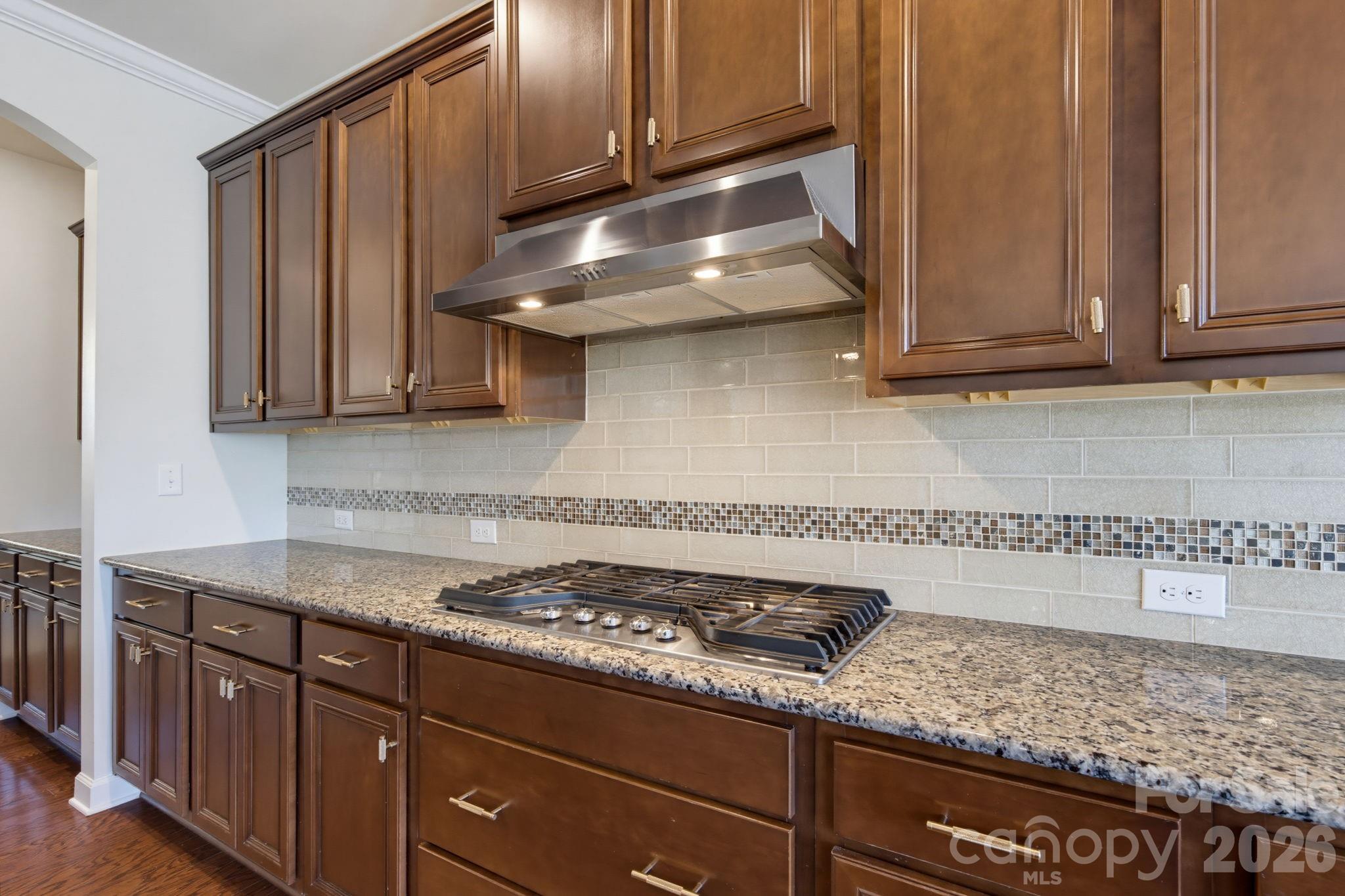 A gas cooktop, vent hood, and expansive counter space give the kitchen a practical, well-equipped workspace. - 8315 Breton Way, Harrisburg
