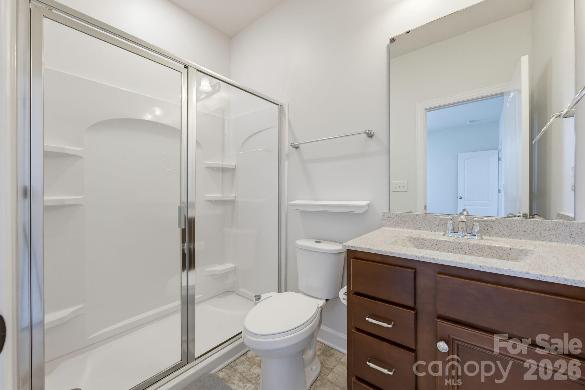 The first-level en-suite guest bath includes a spacious vanity and a walk-in shower with built-in storage shelving. - 8315 Breton Way, Harrisburg