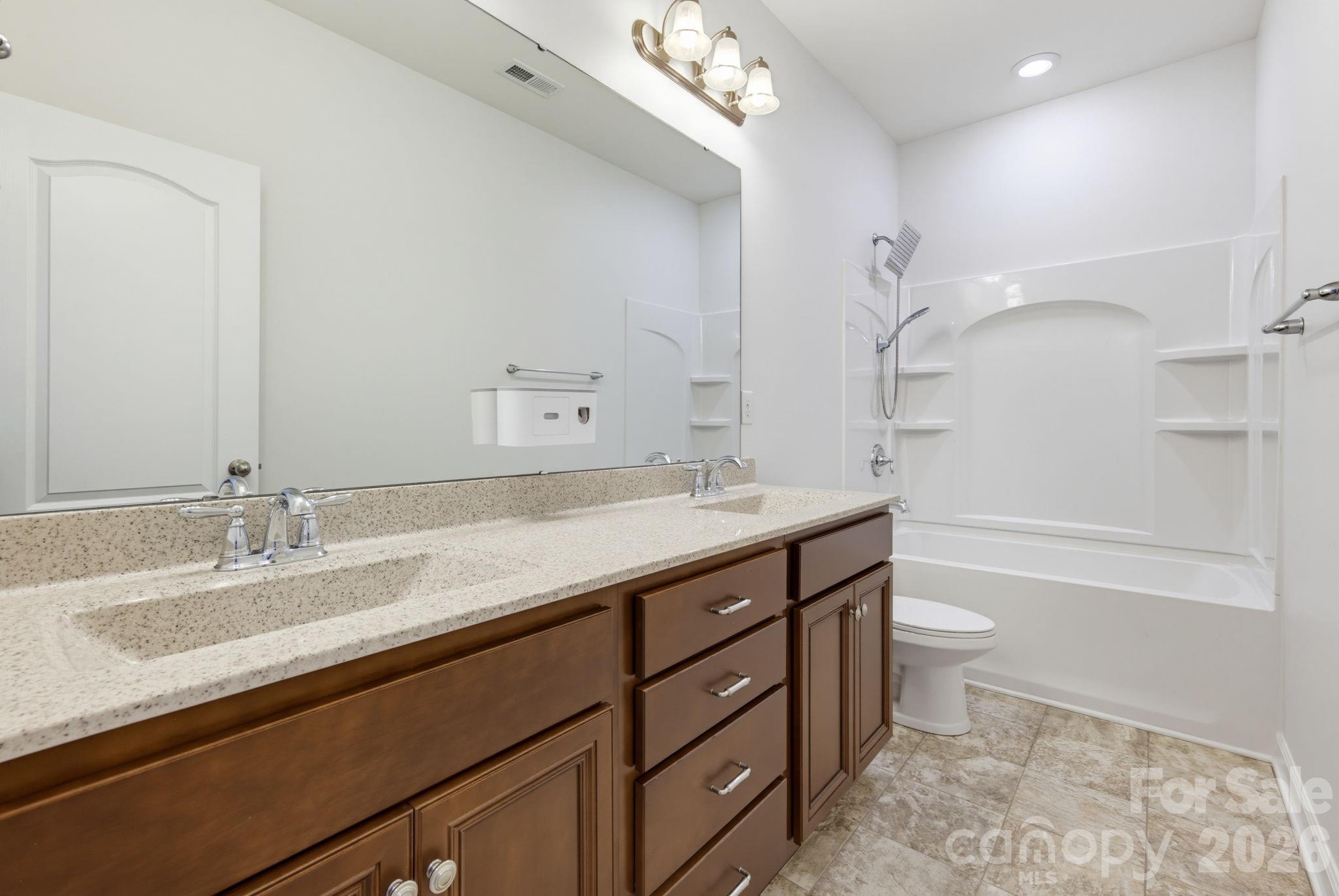 The second-level en suite bathroom includes double sinks, a tub-and-shower combination, and built-in shower shelving for everyday storage. - 8315 Breton Way, Harrisburg