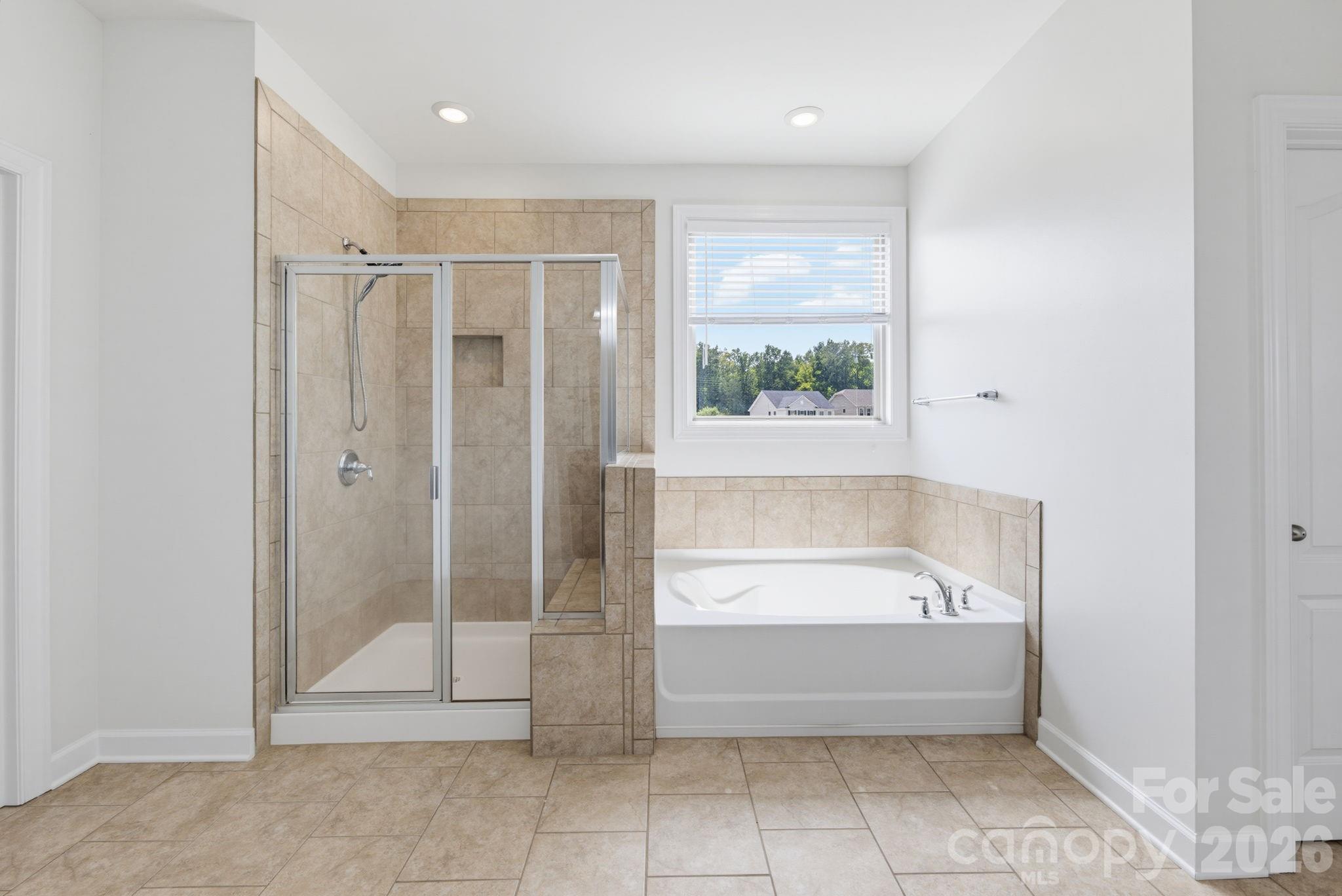 A tiled shower and separate soaking tub create a relaxing primary-bath retreat at the end of the day. - 8315 Breton Way, Harrisburg
