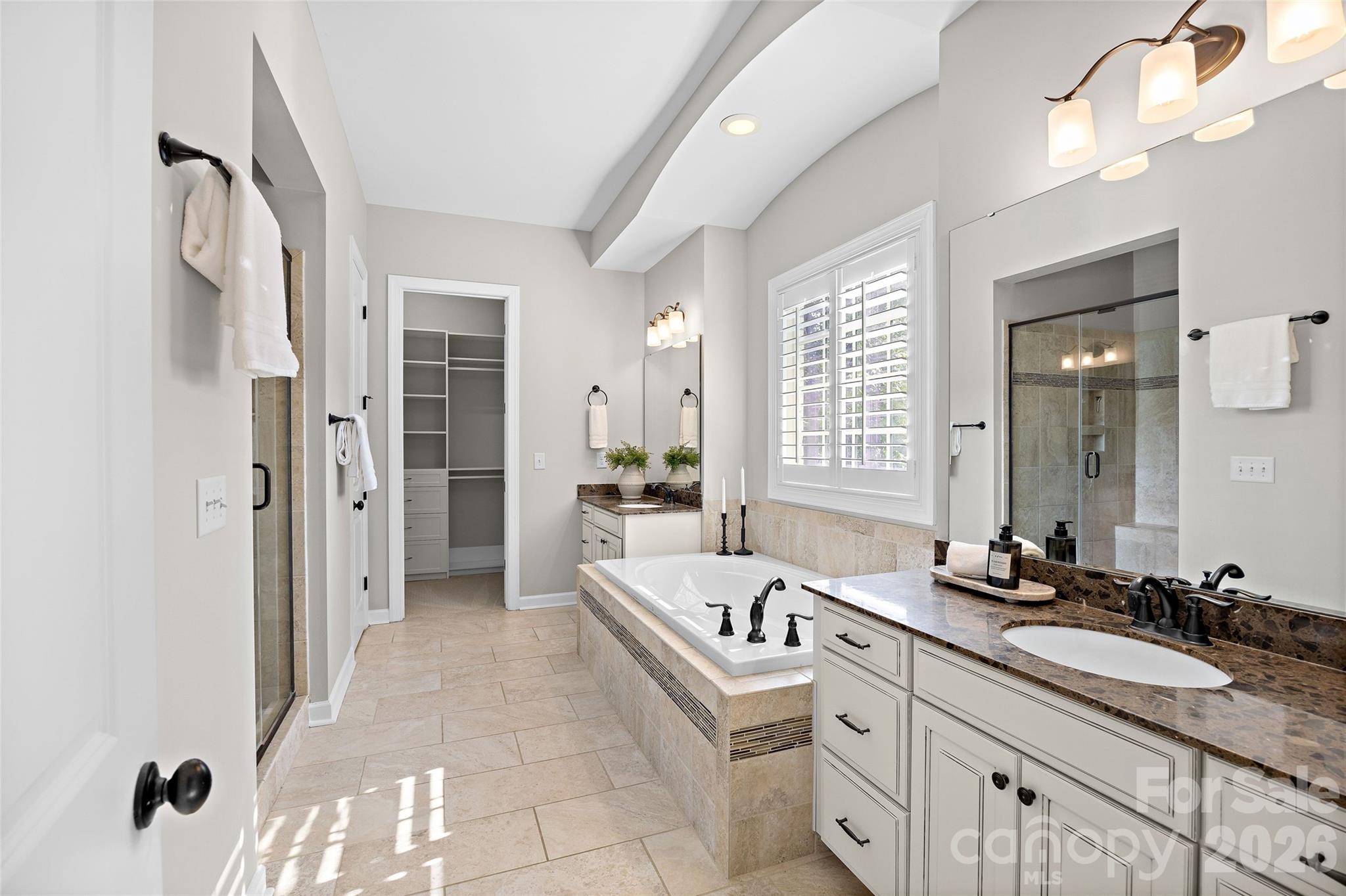 The beautiful primary bath features a dual vanities, two walk-in closets, a whirpool tub, separate walk-in shower and private water closet - 1623 Hawkstone Drive, Waxhaw