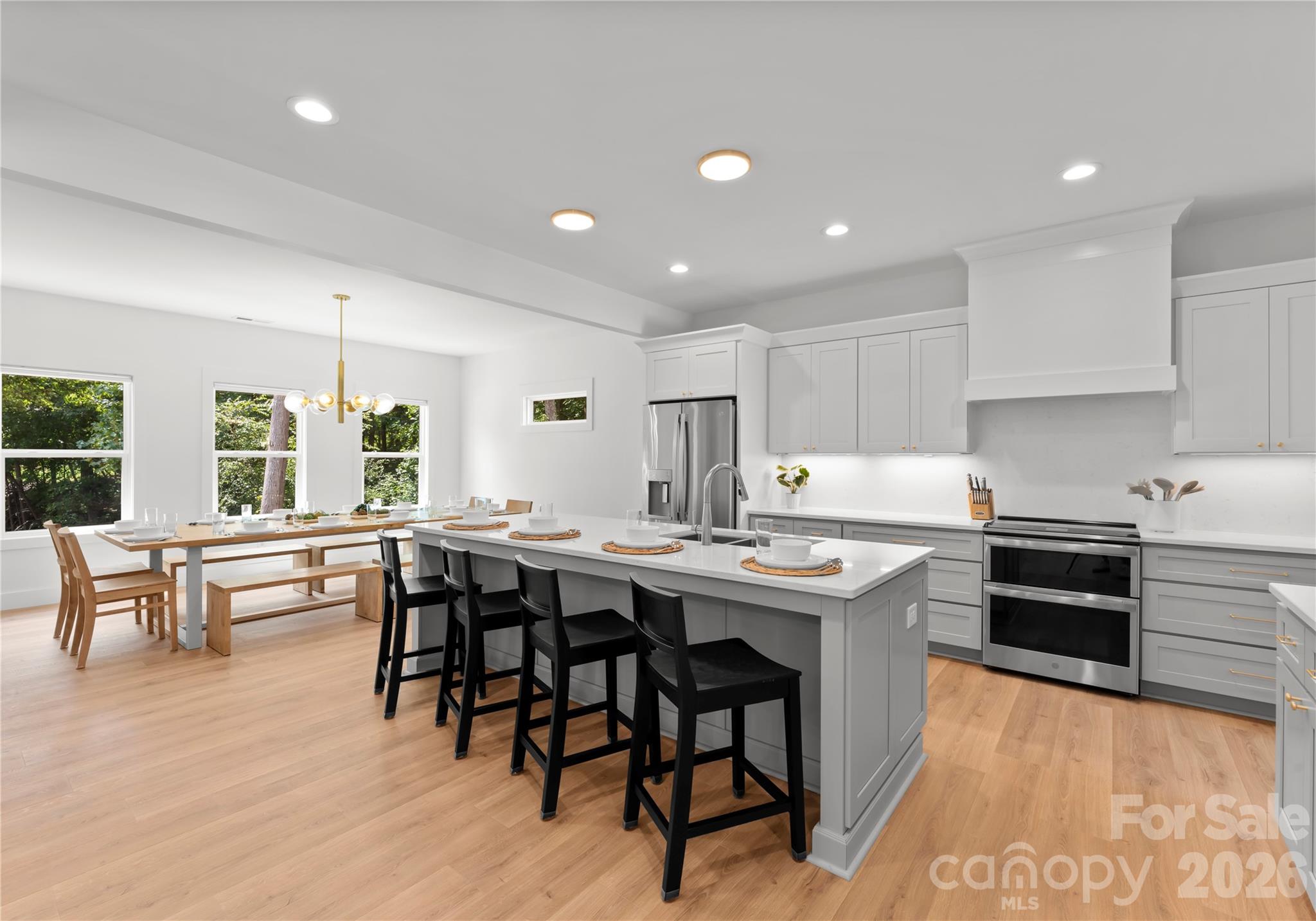 A spacious island anchors the kitchen, designed for effortless entertaining with casual seating and a generous dining area framed by a wall of windows that fills the space with natural light and views. - 143 Hideaway Lane, Mooresville