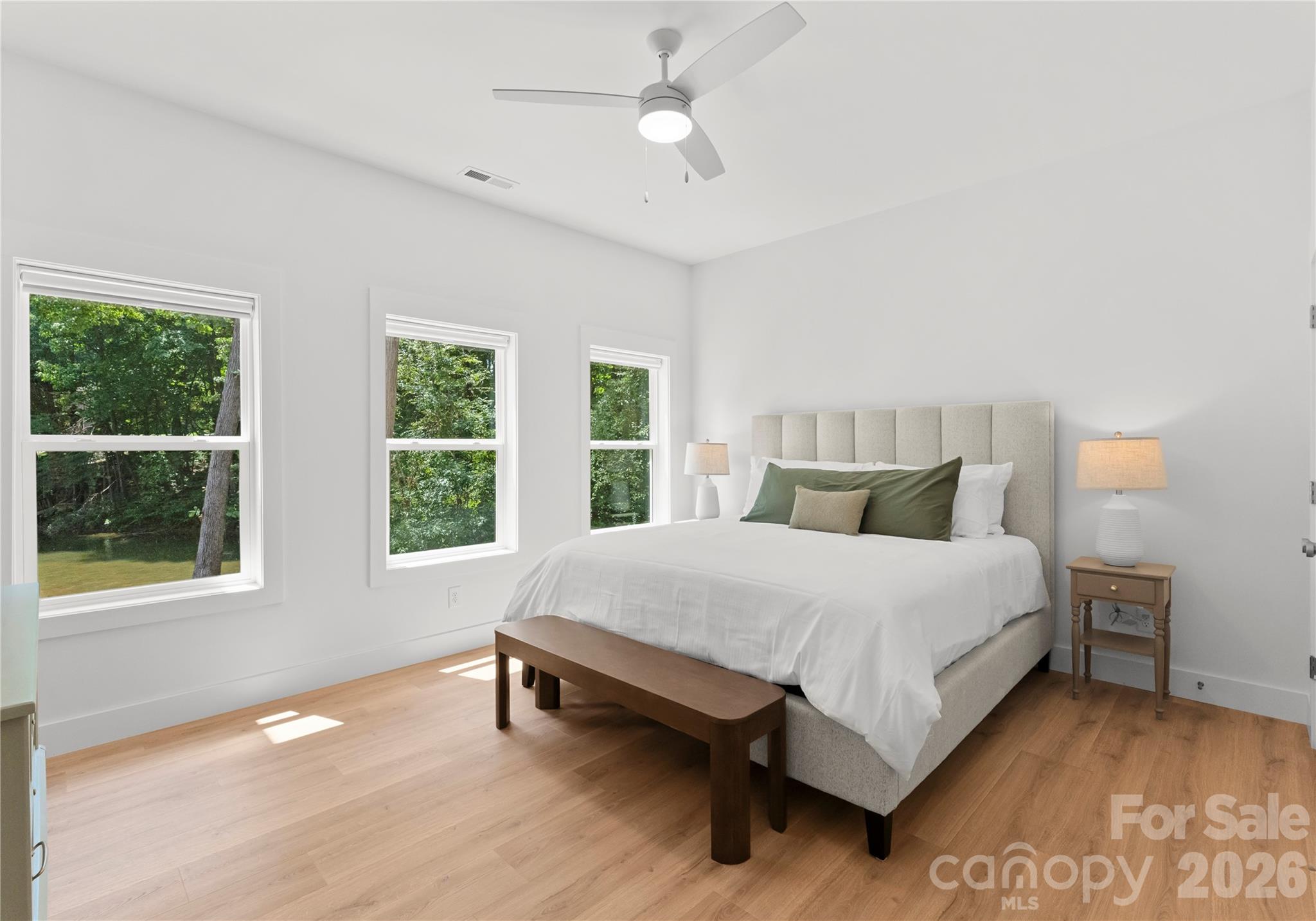 Three windows fill this spacious bedroom with natural light and views of the wooded grounds. - 143 Hideaway Lane, Mooresville