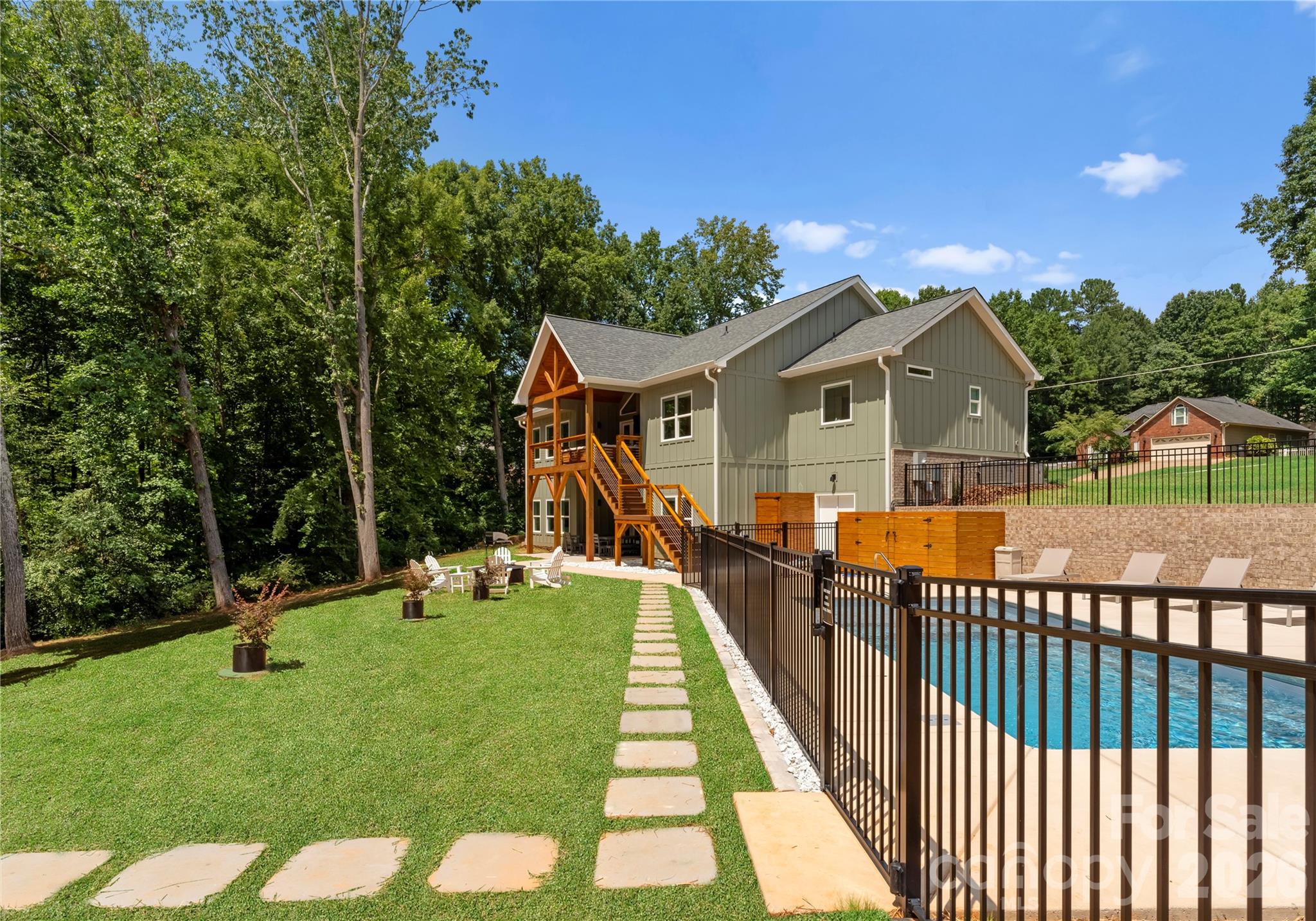 A broad lawn and fenced pool provide room to swim, play, and gather, with the wooded shoreline just beyond. - 143 Hideaway Lane, Mooresville