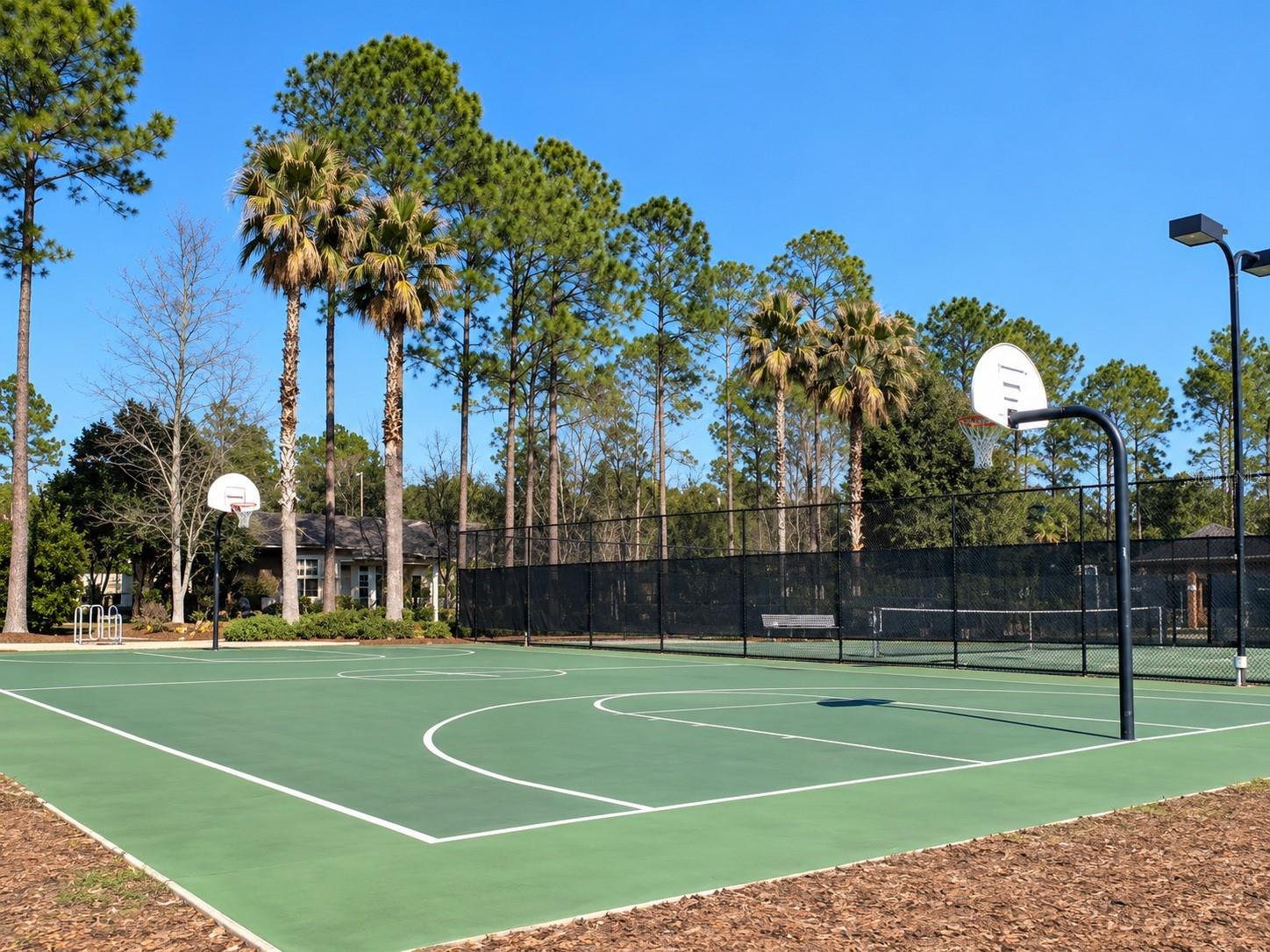 Community basketball court with sports field and lake behind it - 6618 SW 83RD TER, GAINESVILLE