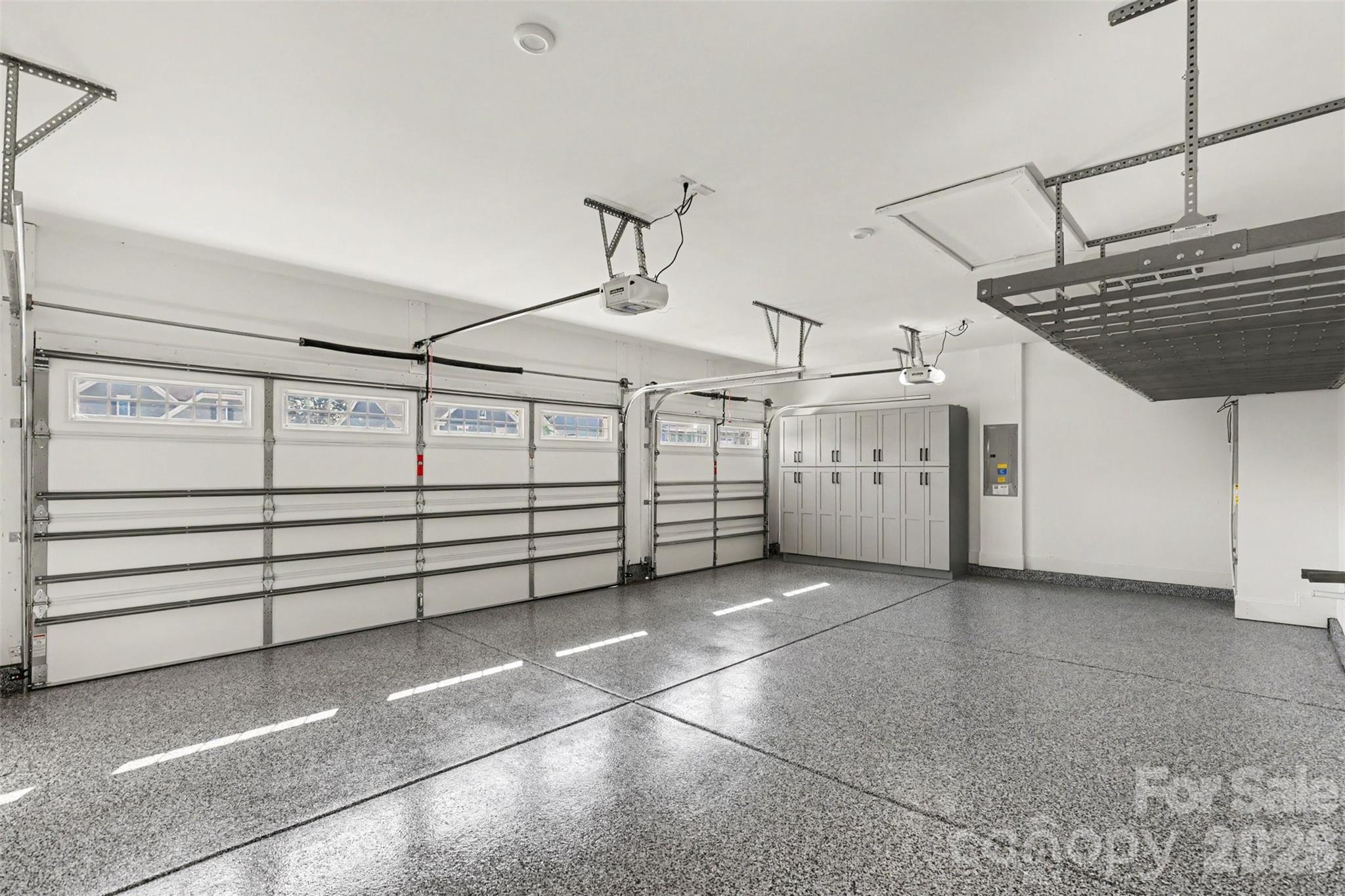 This garage doesn't just park cars. Epoxy floors that shine, a handsome bank of storage cabinets, and an overhead rack for everything you don't want cluttering the floor. Three bays, zero excuses. - 8027 Longwaters Court, York