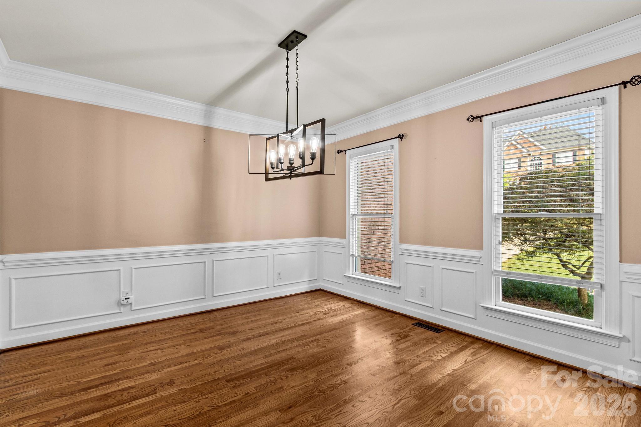 Formal dining room showcases wainscoating, crown molding, and hardwood floors. - 12822 Cadgwith Cove Drive, Huntersville